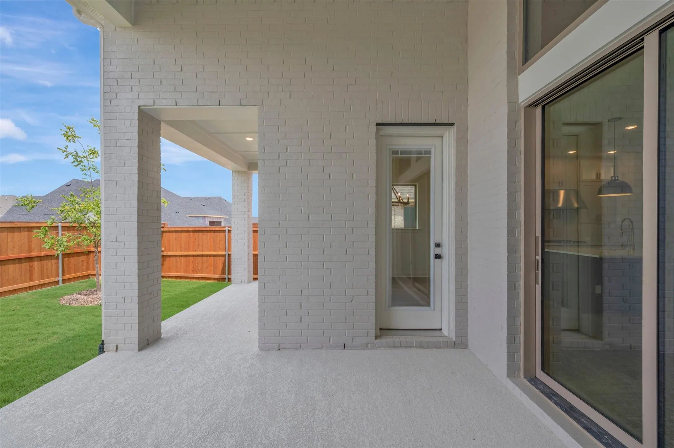 Expansive covered patio with a textured concrete surface and white brick columns