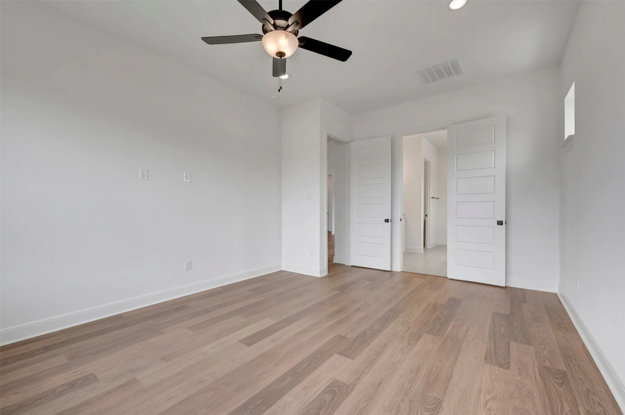 Wood-finish flooring, white walls, ceiling fan, recessed lighting, and white panel doors