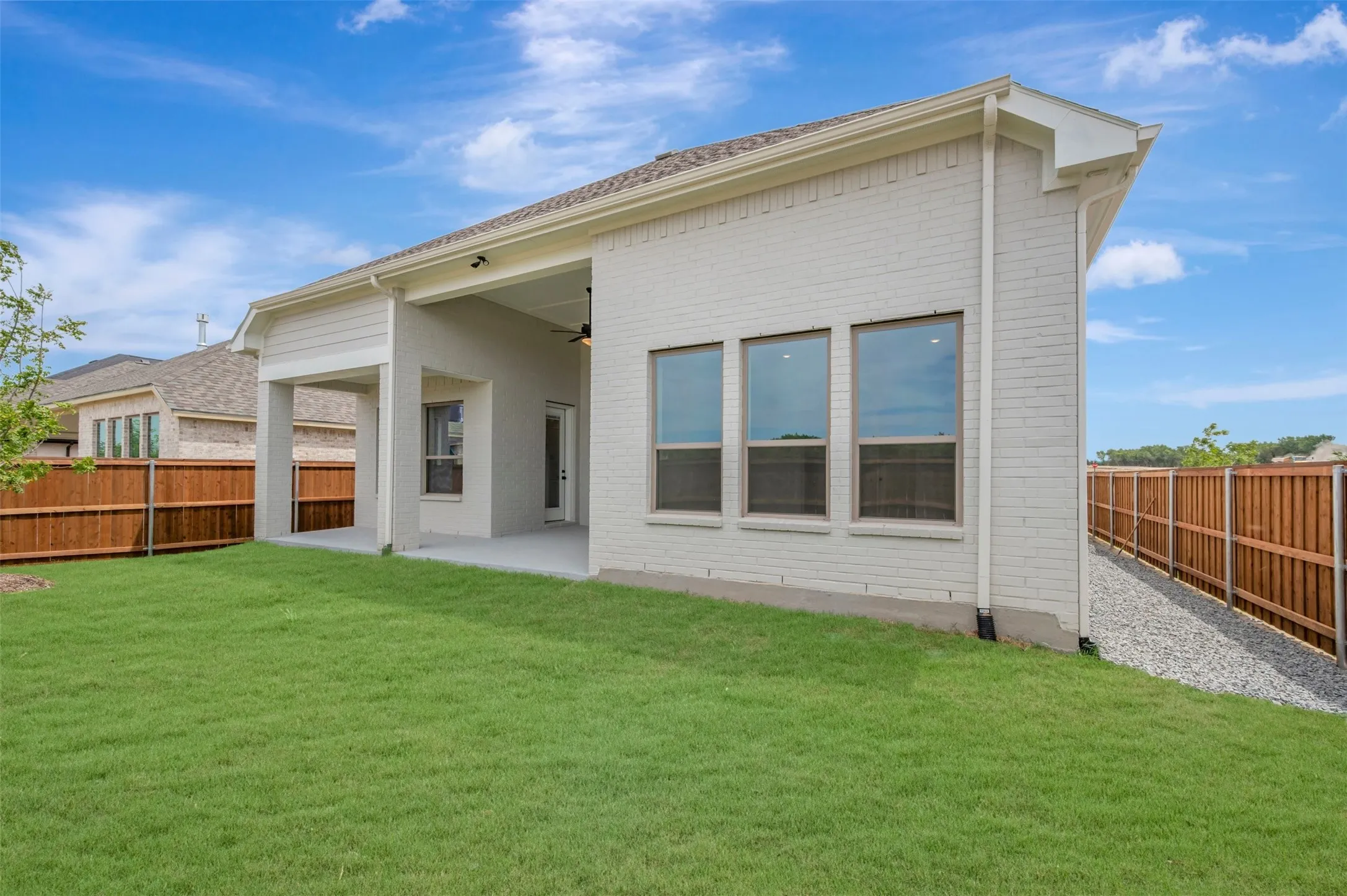 Expansive backyard featuring a lush lawn, covered patio, and privacy fencing