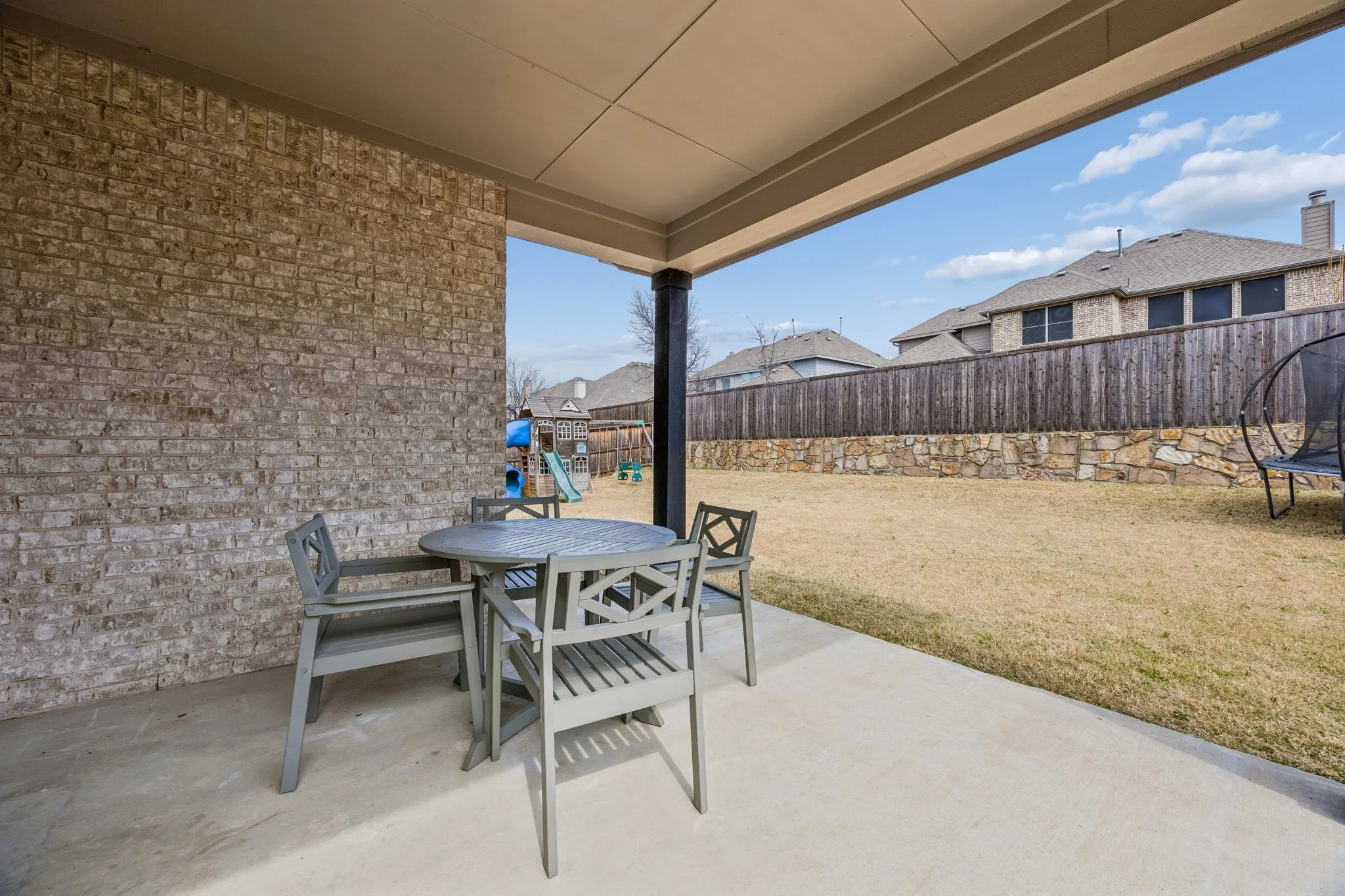 Fenced backyard with a patio, a trampoline, and outdoor dining space