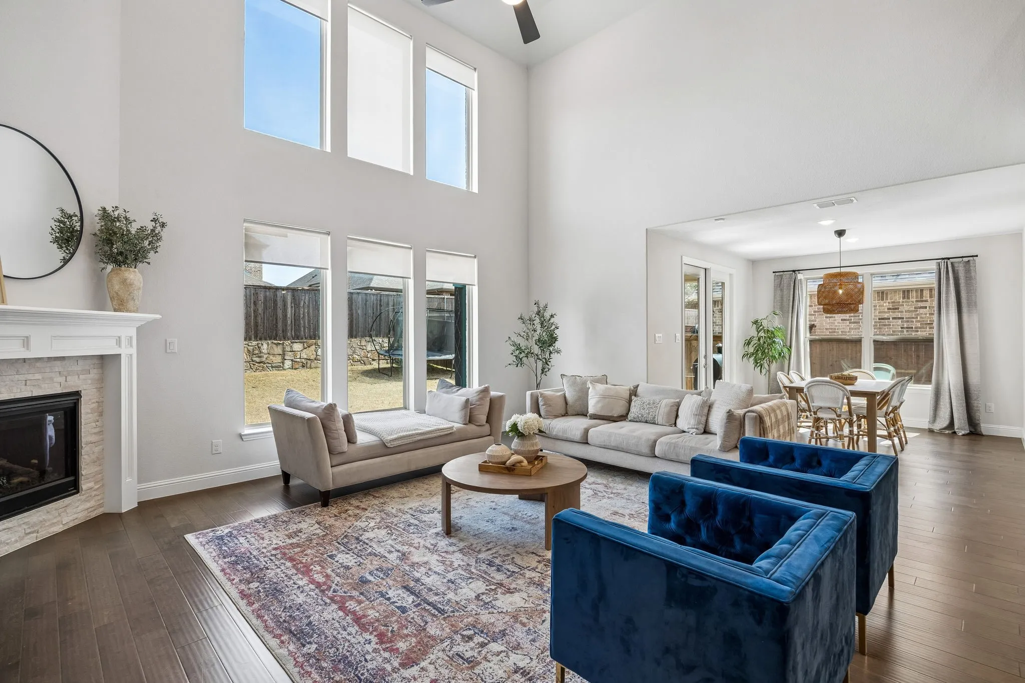 Living area featuring dark wood-style floors, a brick fireplace, a ceiling fan, and a high ceiling