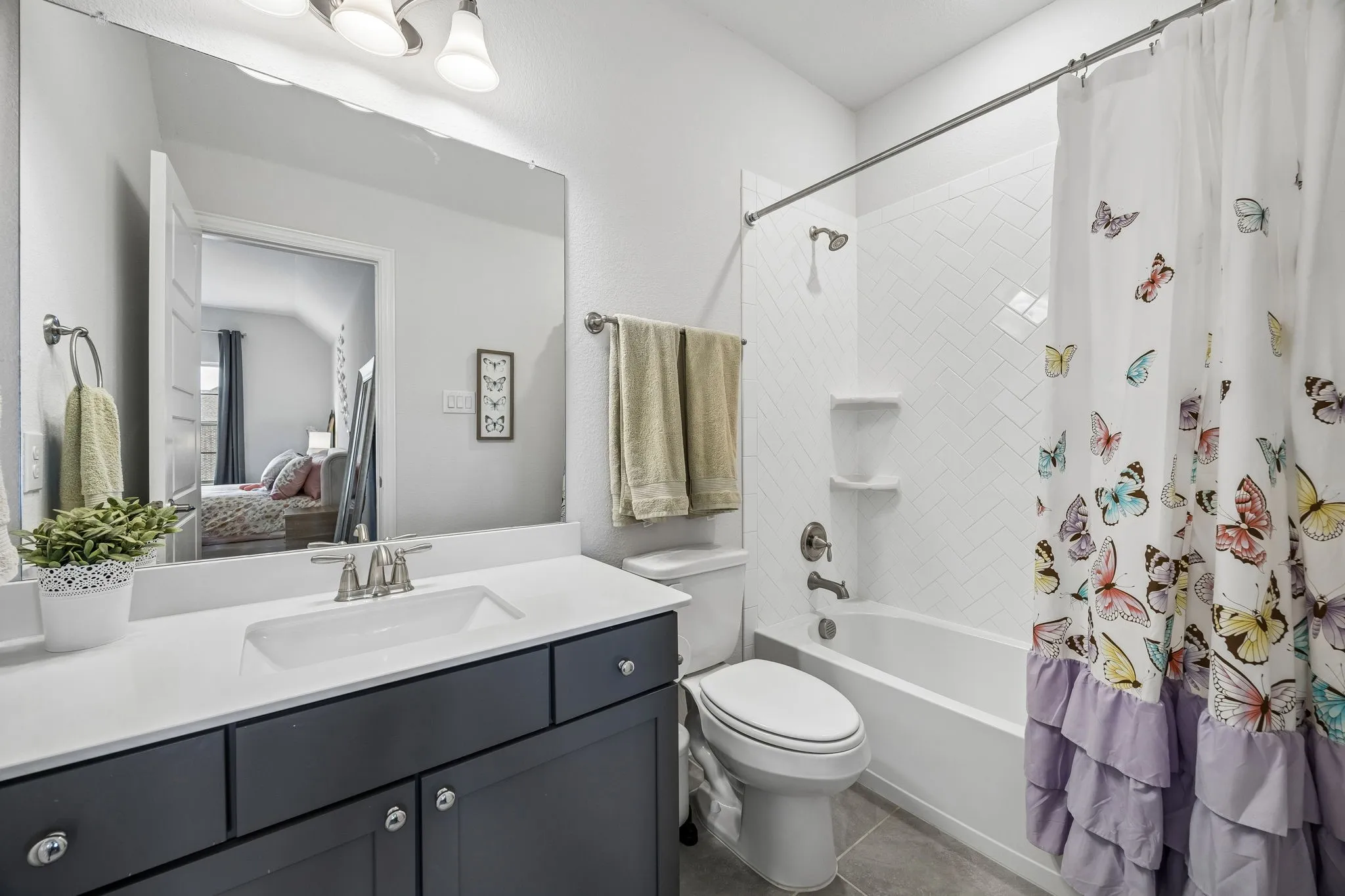 Full bathroom with vanity, shower / bathtub combination with curtain, ensuite bathroom, and dark tile patterned floors