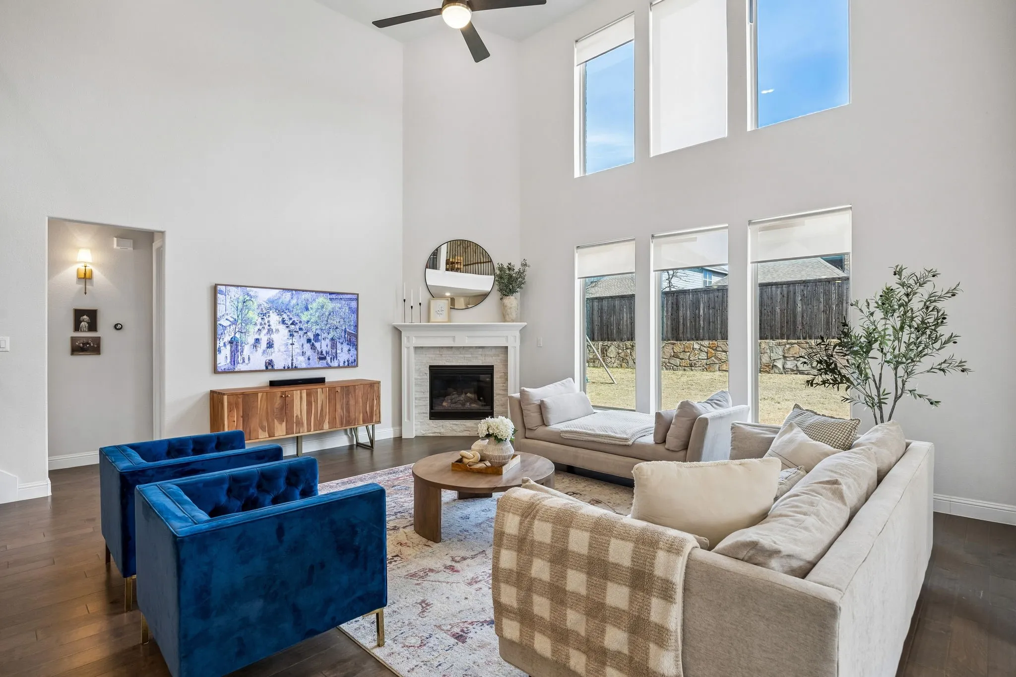Living room with dark wood finished floors, healthy amount of natural light, a stone fireplace, and a high ceiling