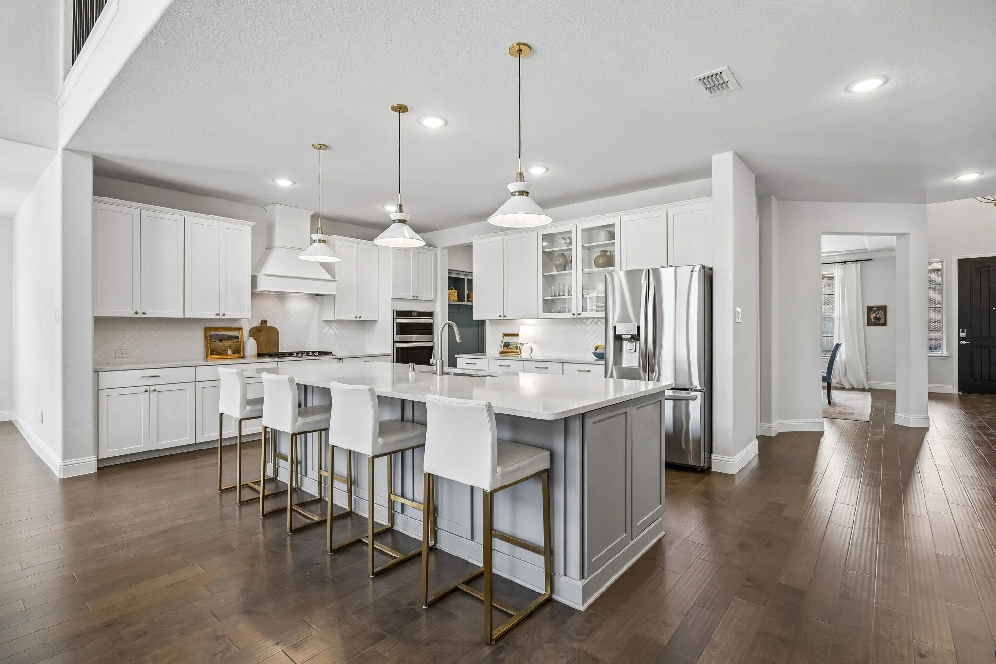 Two tone kitchen with a spacious island, stainless steel appliances, glass insert cabinets, a breakfast bar, and dark wood-type flooring