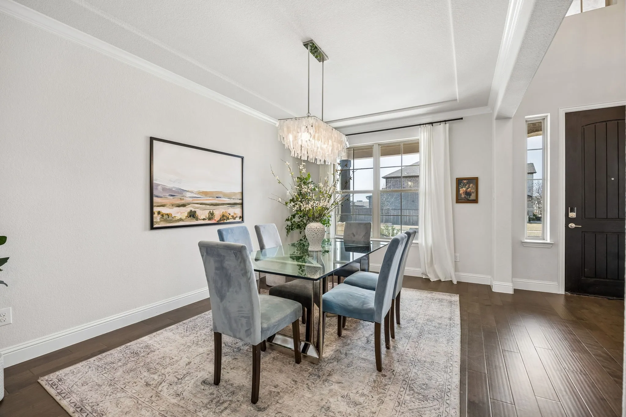 Dining space with suspended lighting, ornamental molding, and dark wood-style floors
