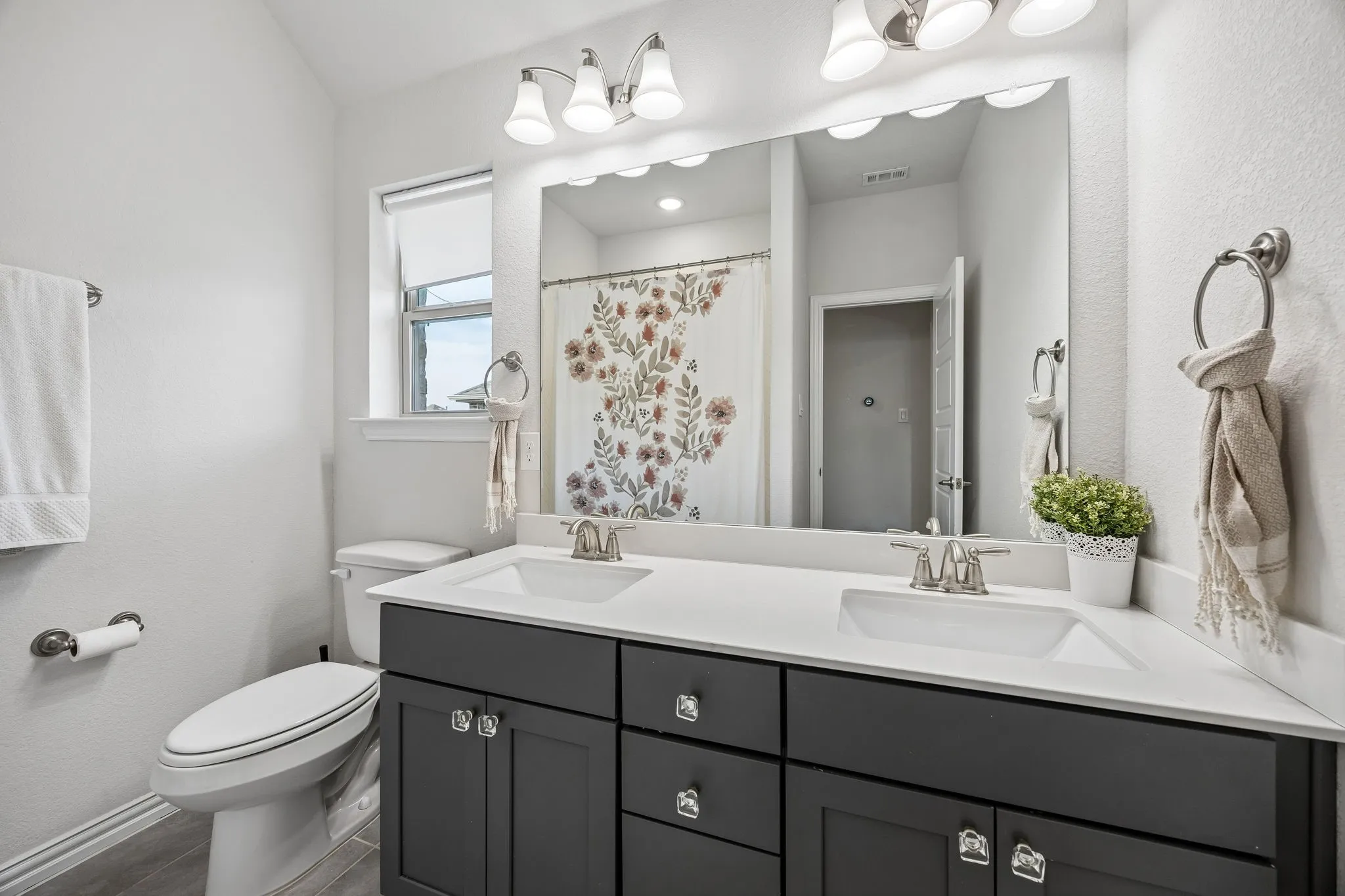 Bathroom with double vanity, a shower with shower curtain, and a textured wall