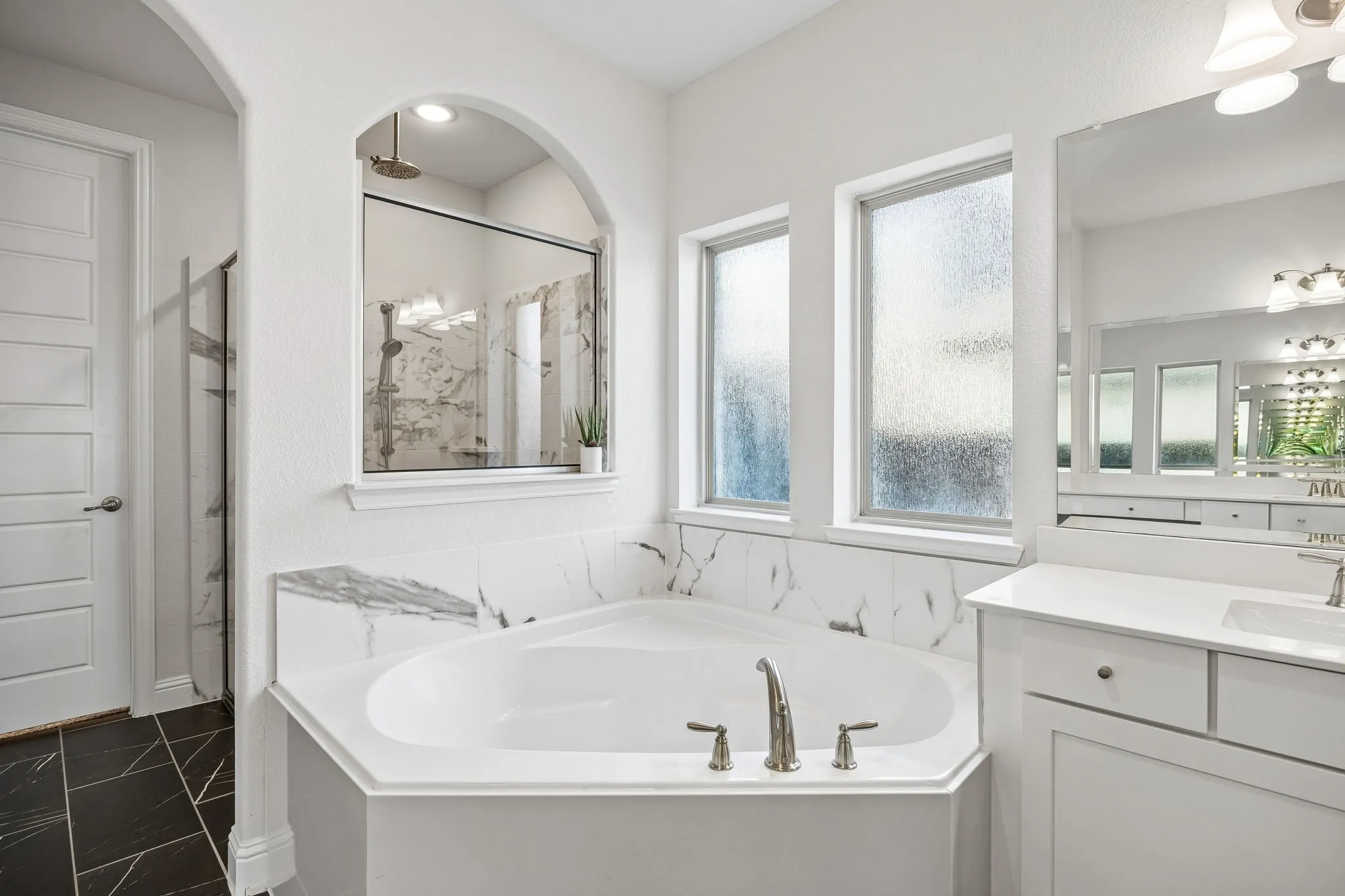 Full bath featuring a marble finish shower, a garden tub, and vanity