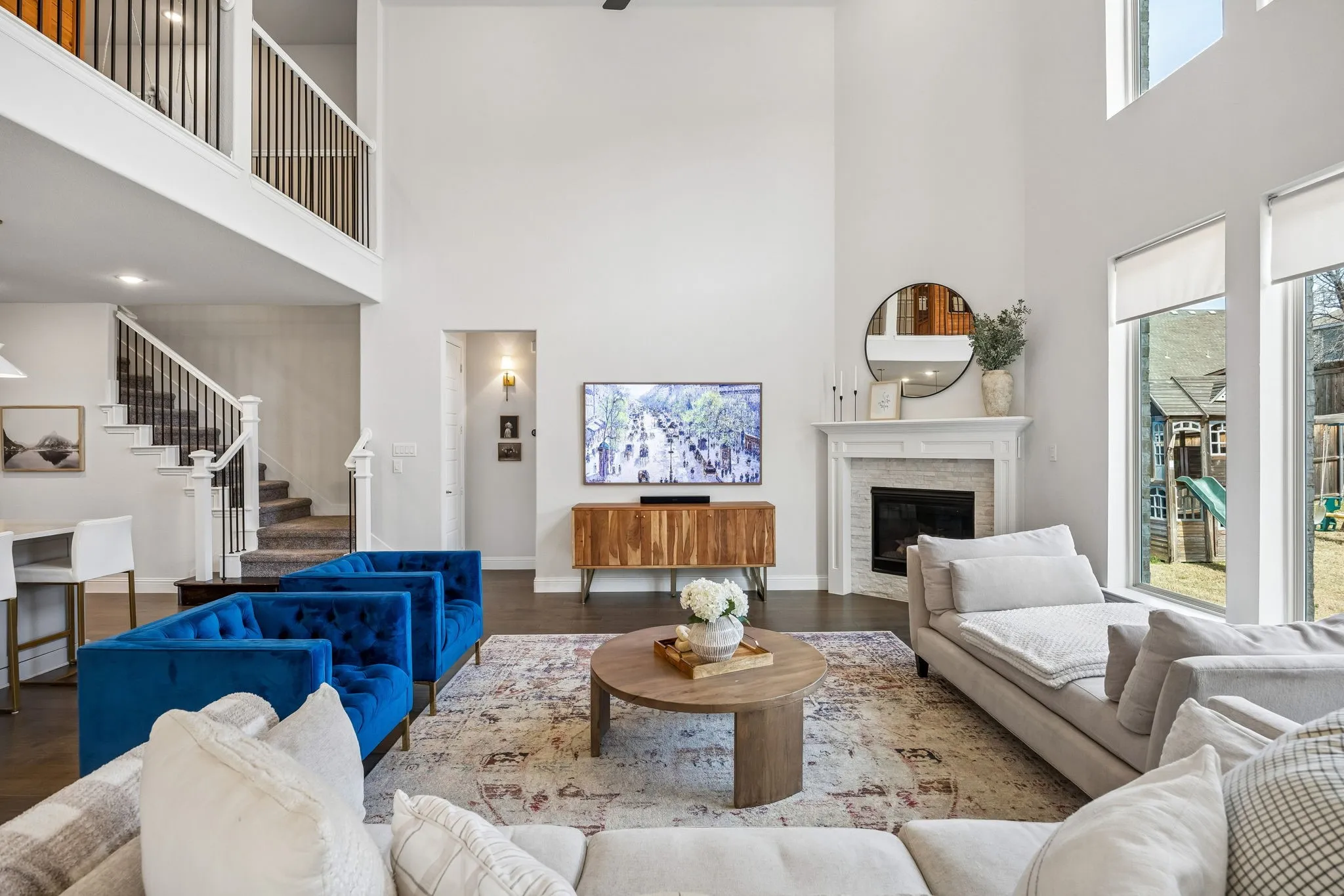 Living area featuring wood finished floors, a stone fireplace, and a high ceiling