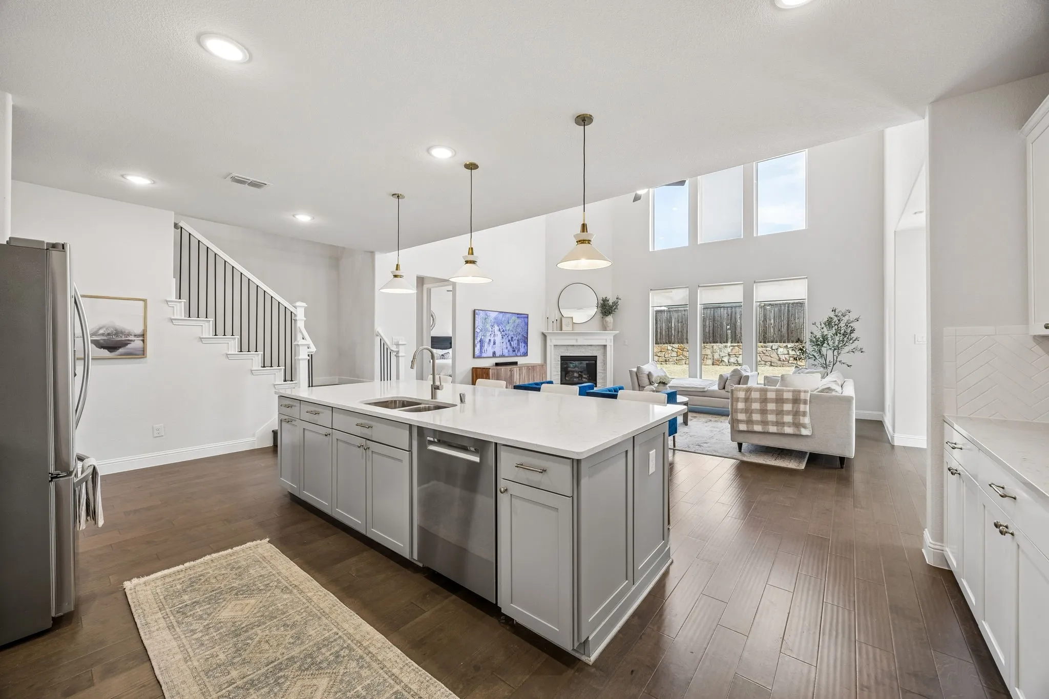Kitchen with open floor plan, a fireplace, stainless steel appliances, gray cabinetry, and dark wood-style flooring