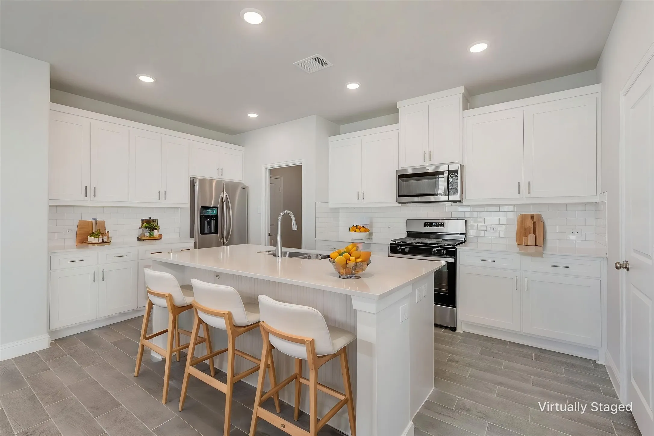 Expansive kitchen featuring white shaker cabinetry, stainless steel appliances, subway tile backsplash, a large center island, and wood-finish flooring