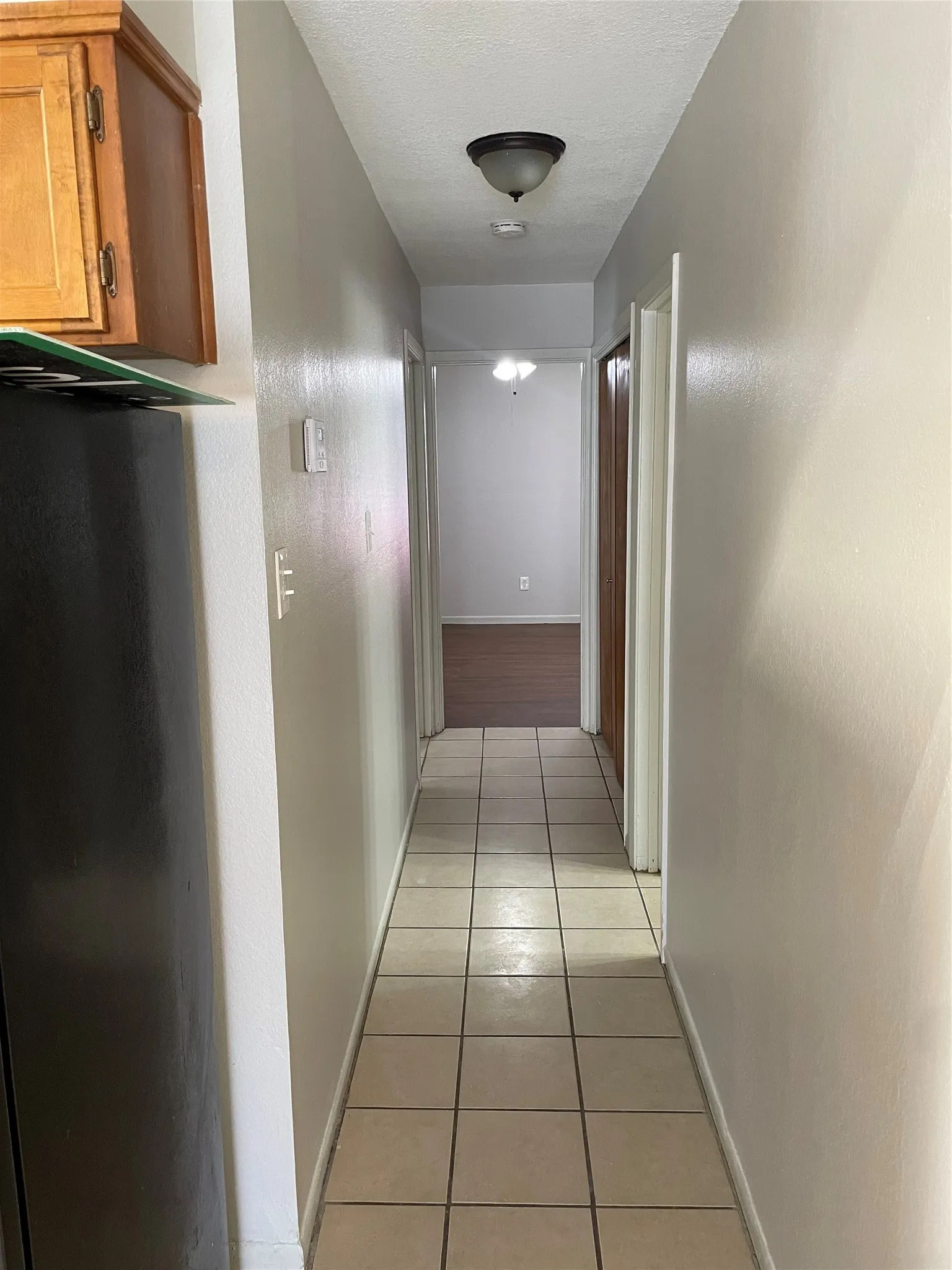 Corridor featuring light tile patterned flooring and a textured ceiling