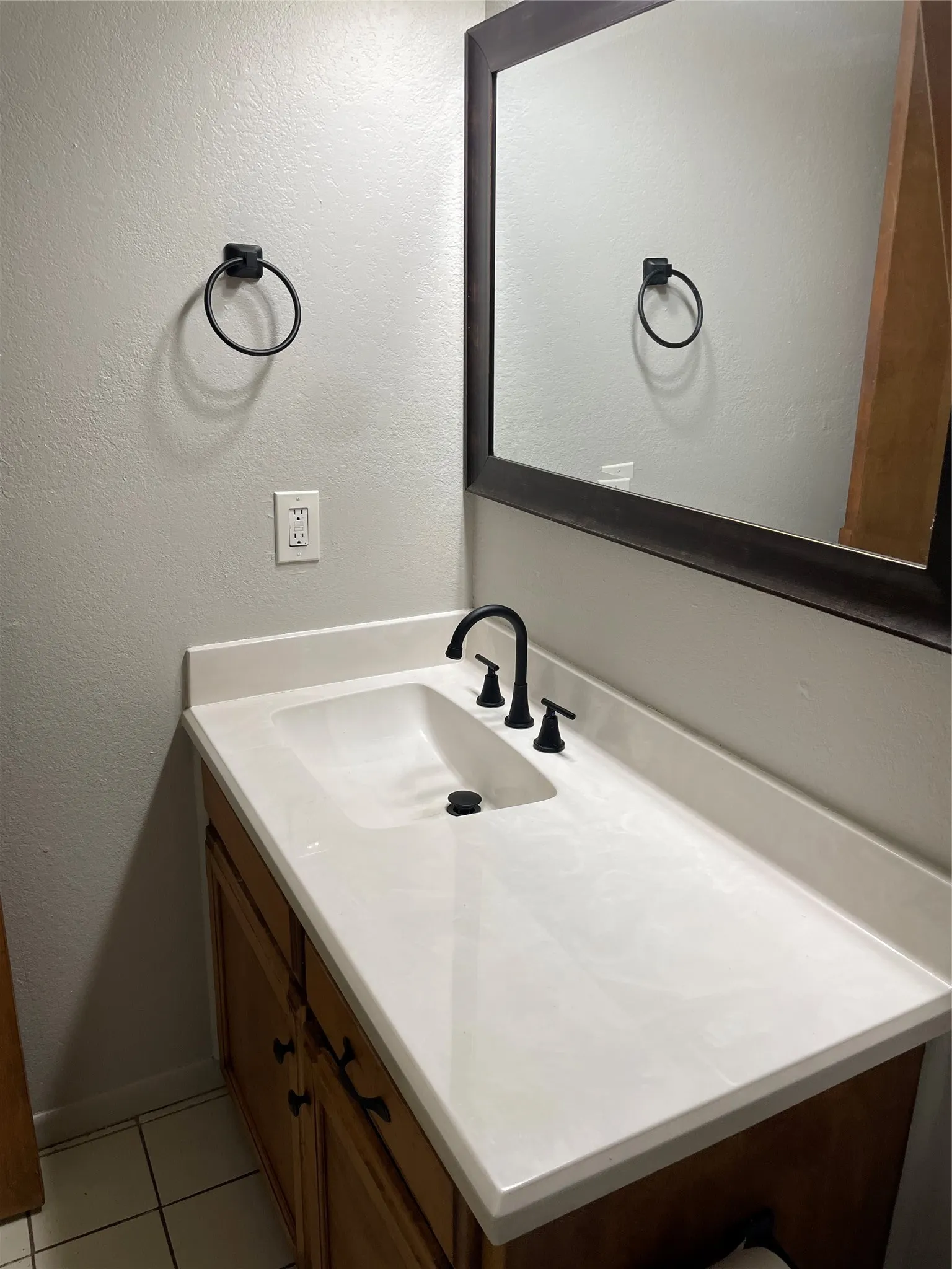 Bathroom with vanity, light tile patterned floors, and a textured wall