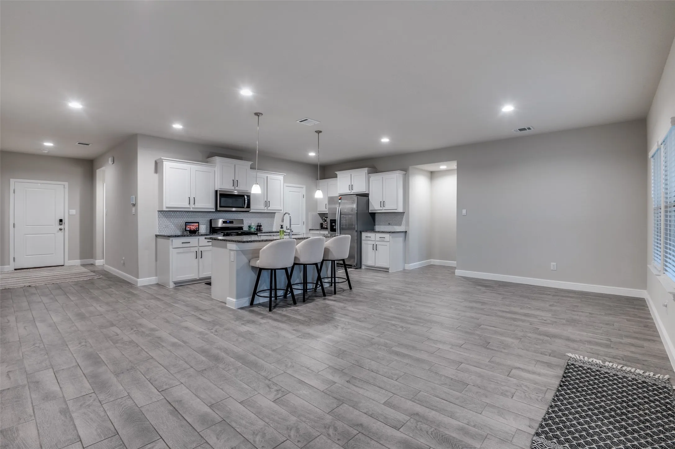 Kitchen with white cabinets, a center island with sink, decorative light fixtures, and a breakfast bar area