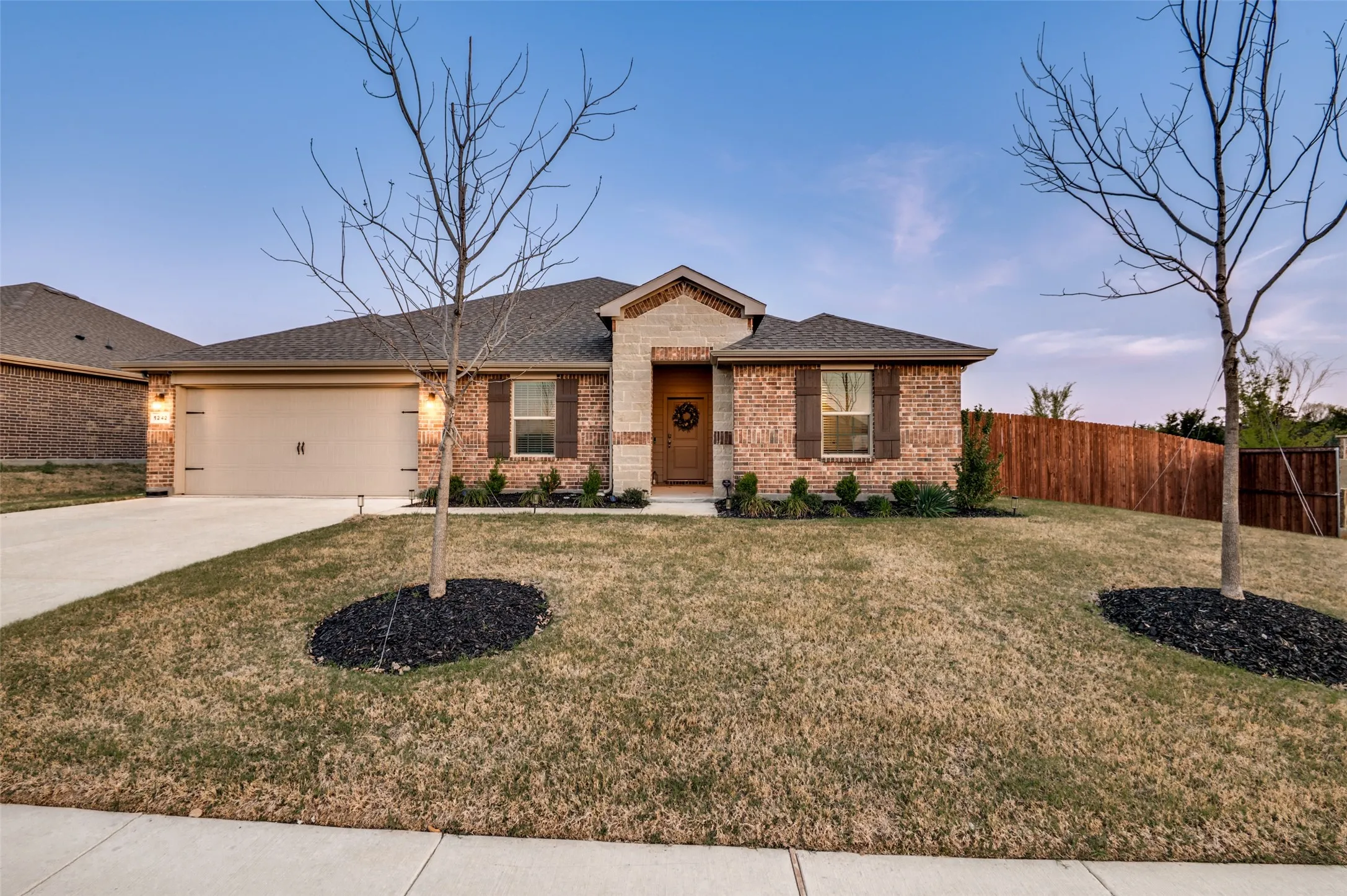 Ranch-style home with brick siding, driveway, a garage, and roof with shingles