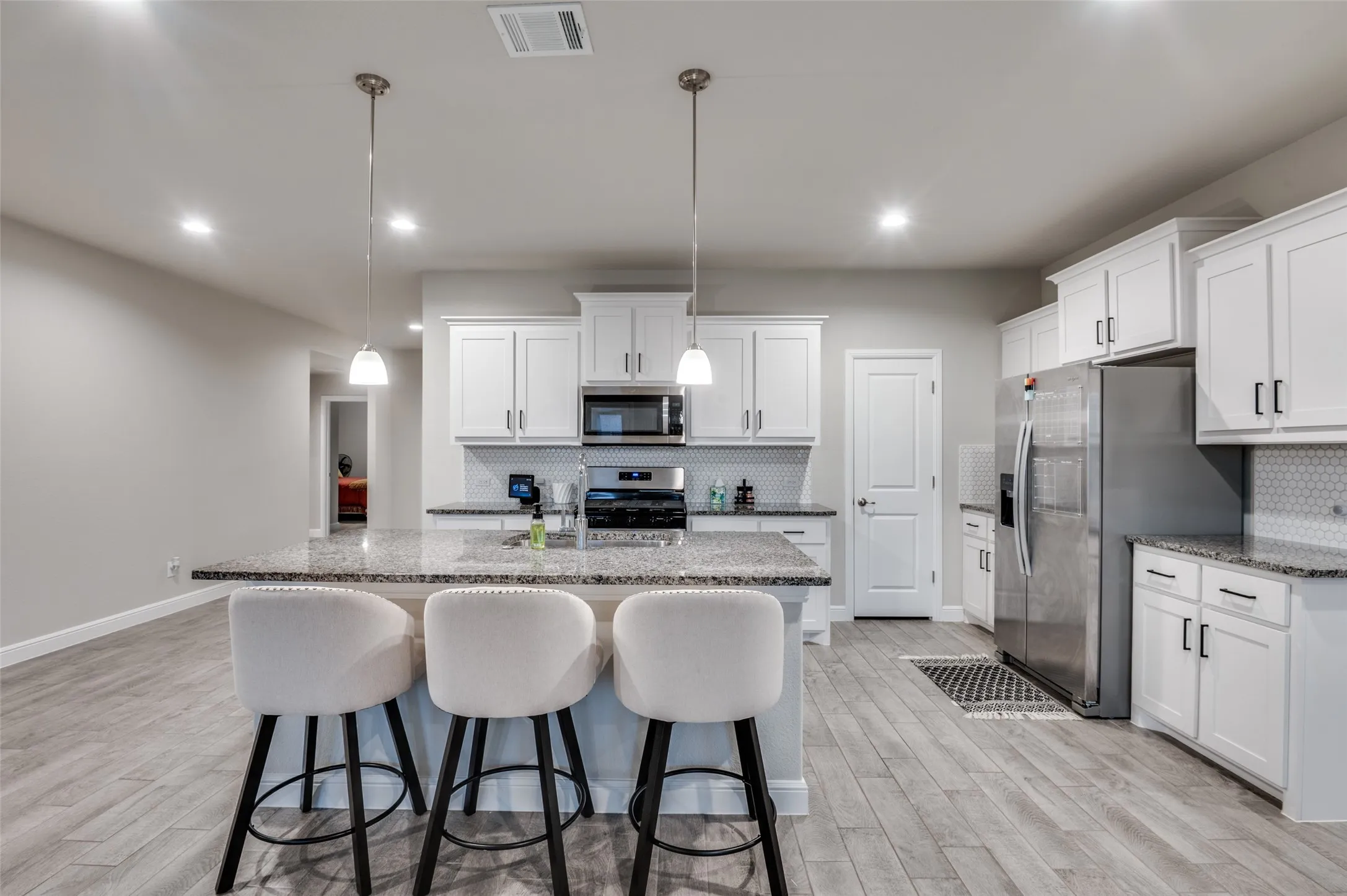 Kitchen featuring a breakfast bar, light stone counters, a center island with sink, and stainless steel appliances