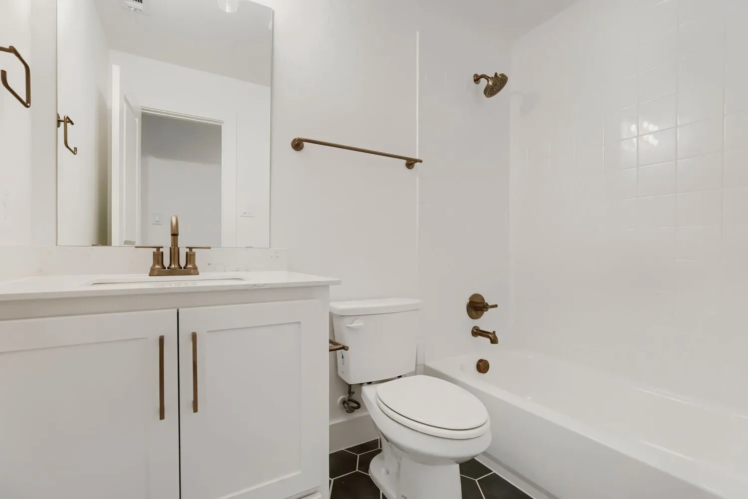 White vanity with a quartz countertop, bronze-finish faucet, and integrated sink