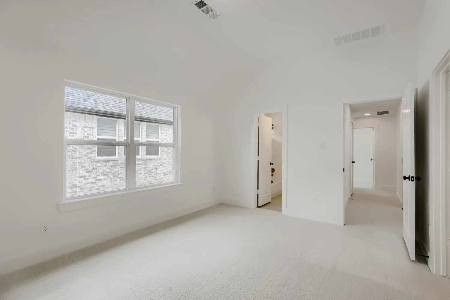 White carpeted flooring, white painted walls, white trim, recessed lighting, and a white framed window