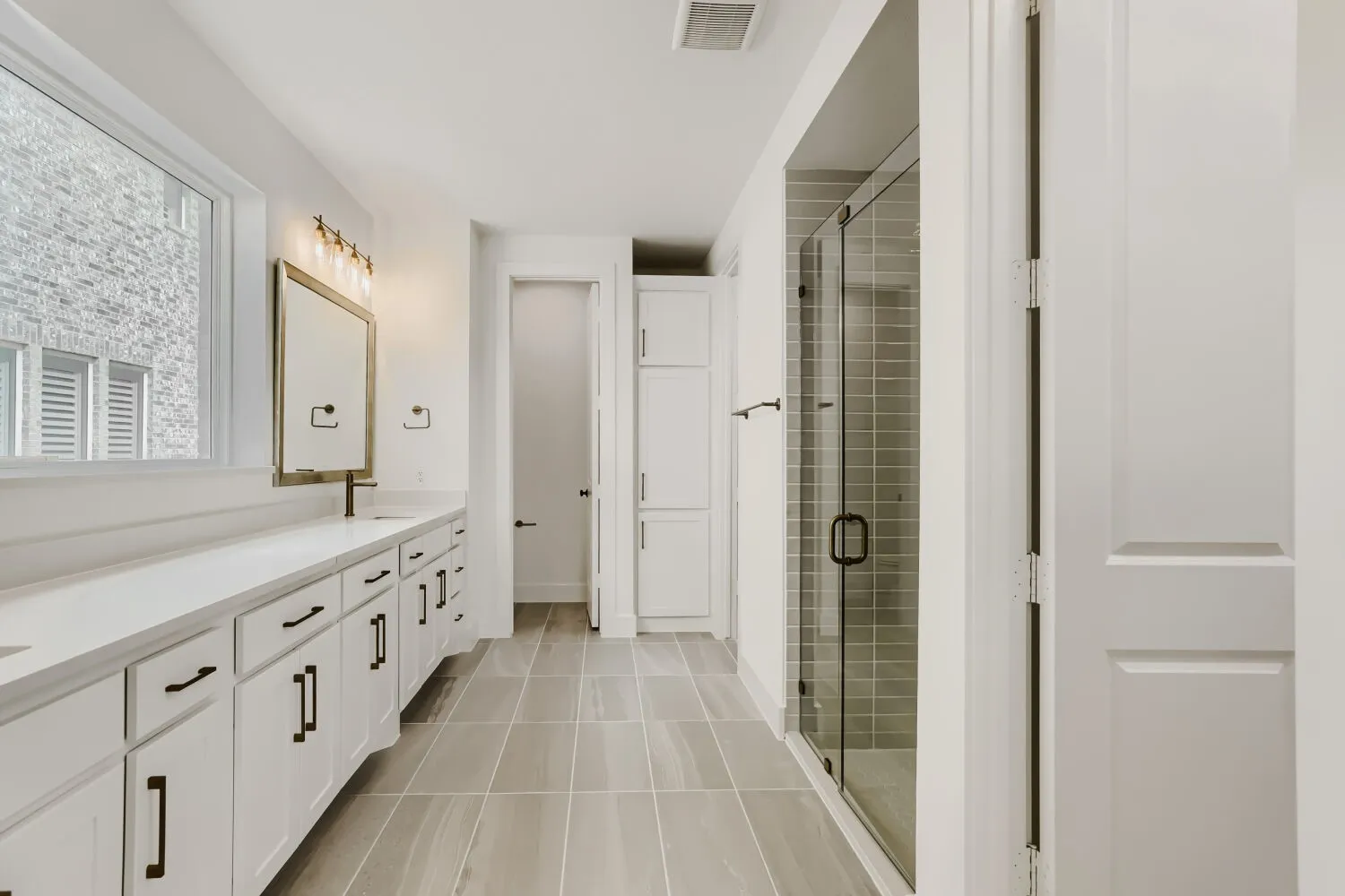 Dual vanity with white cabinetry, solid surface countertops, and dark hardware