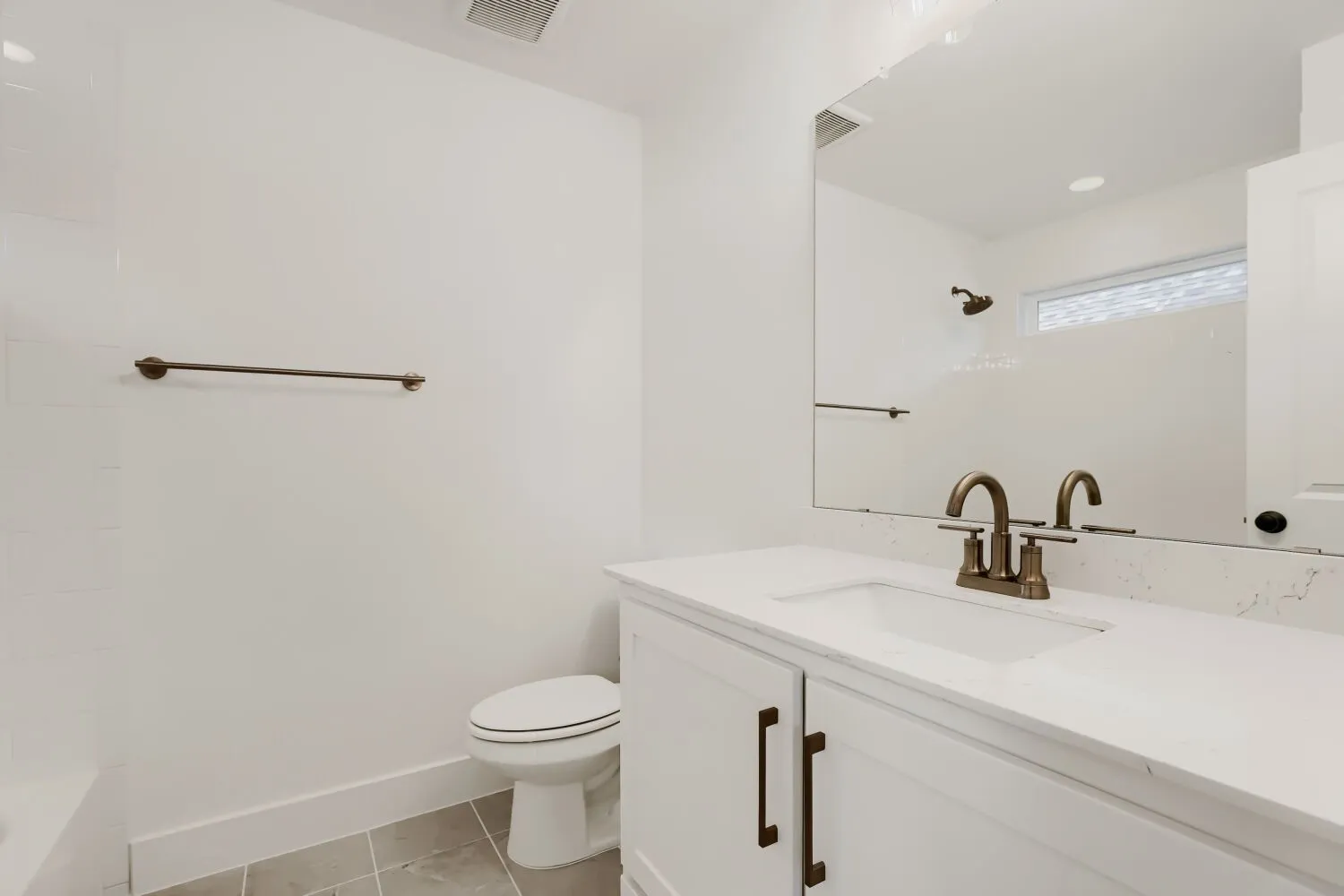 White vanity with integrated sink, bronze-finish faucet, and quartz-finish countertop