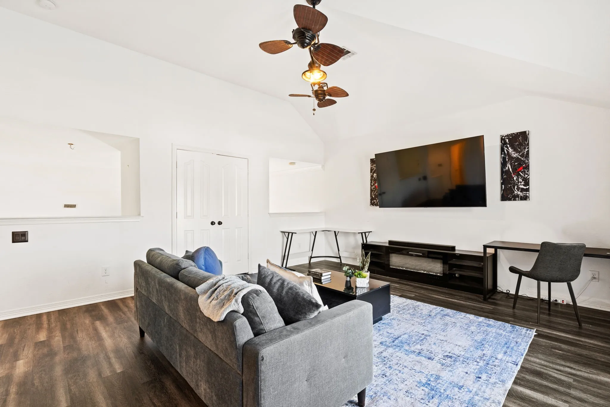 Living area with ceiling fan, dark wood-style floors, and lofted ceiling