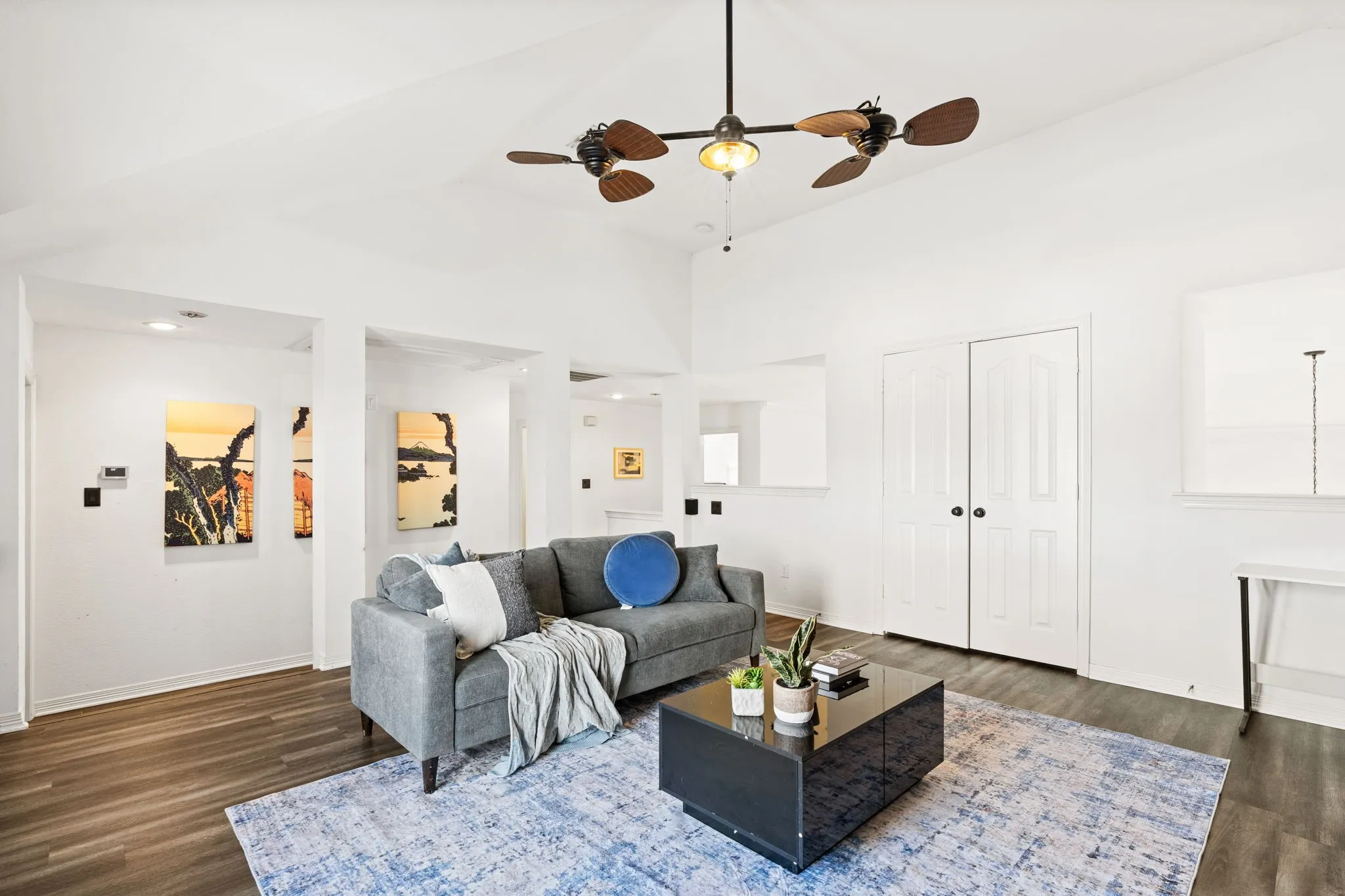 Living room featuring dark wood-type flooring, a ceiling fan, and a high ceiling