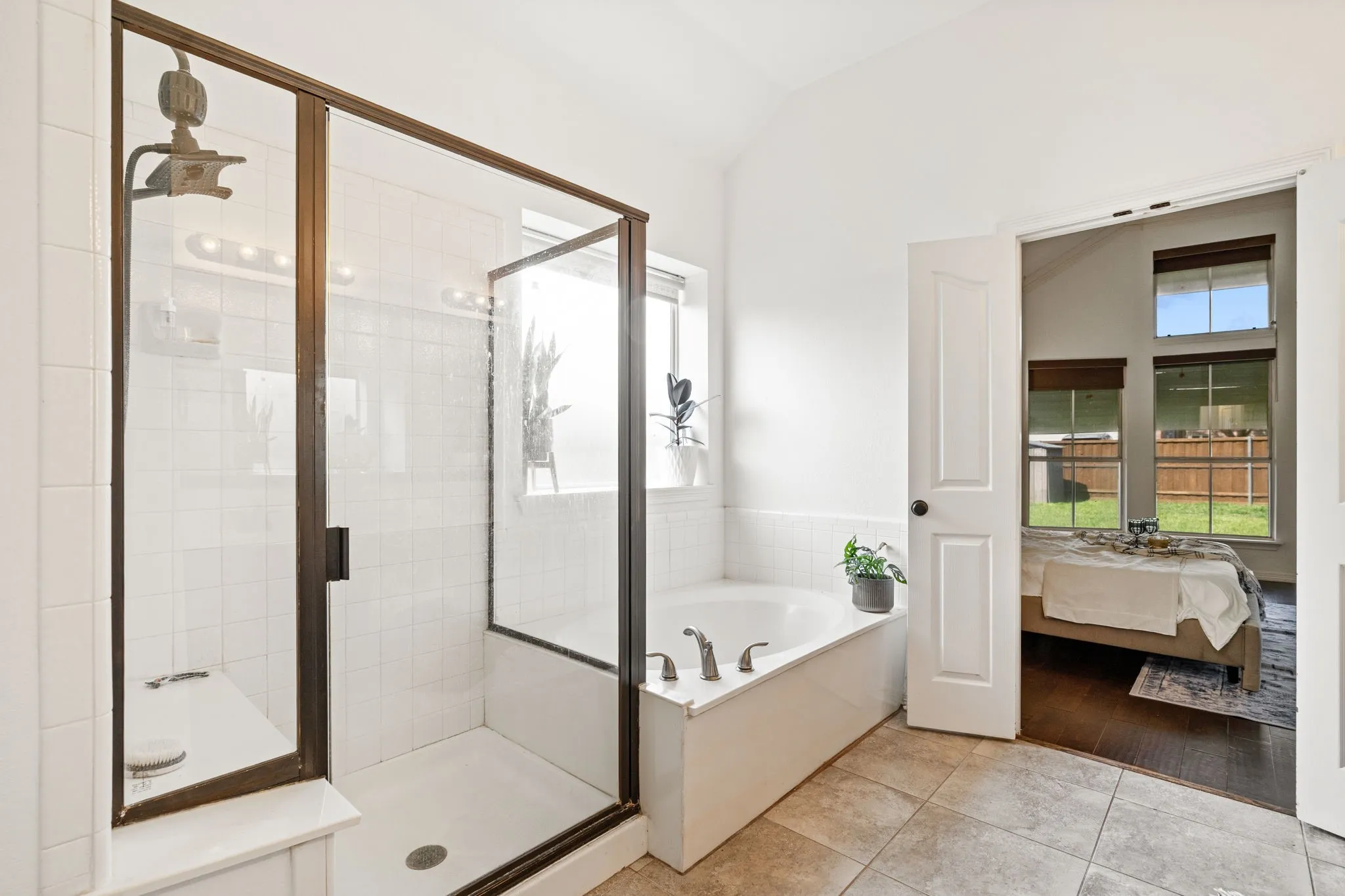 Bathroom with connected bathroom, a garden tub, a stall shower, light tile patterned flooring, and lofted ceiling