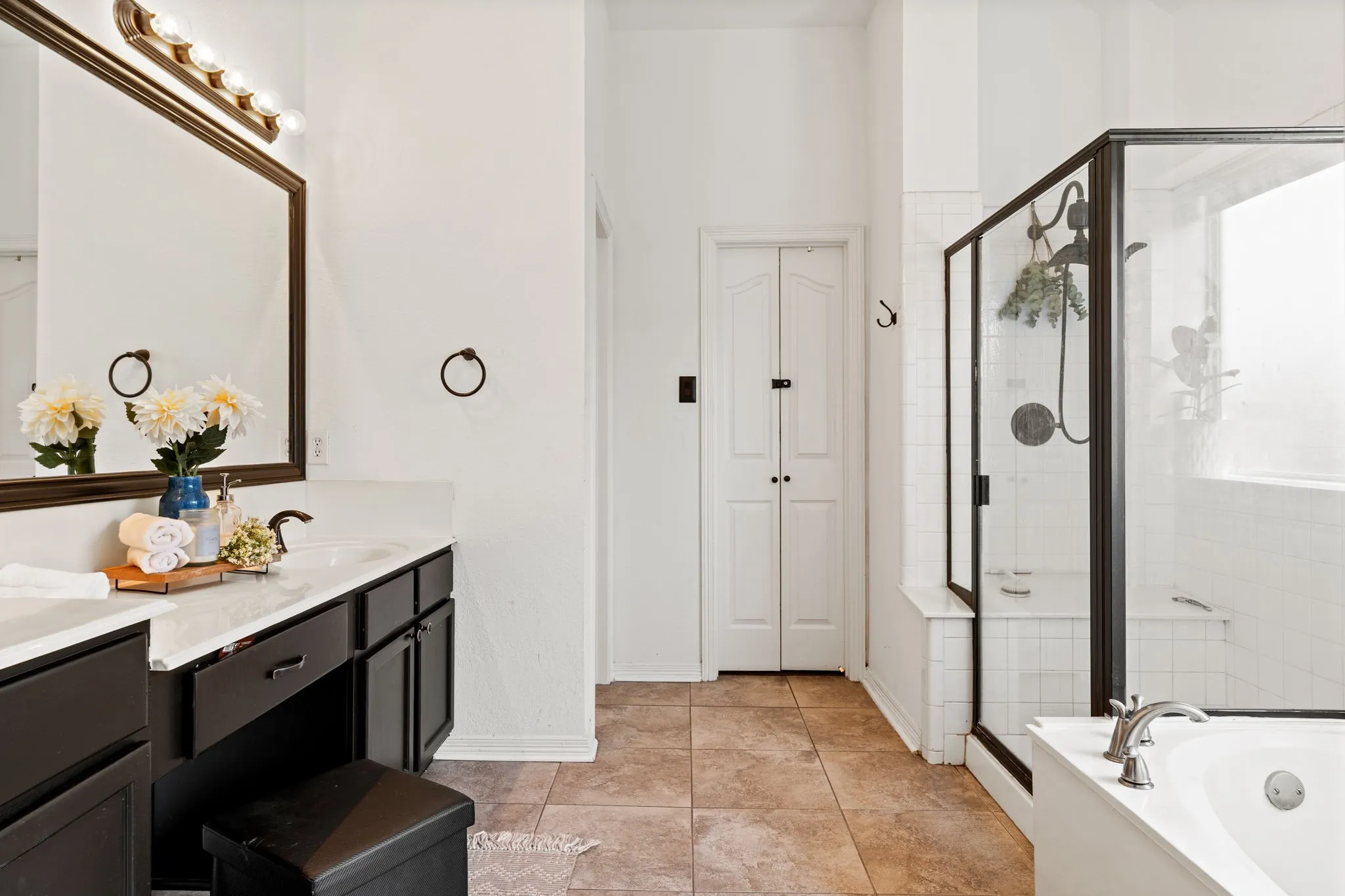 Full bathroom featuring double vanity, a shower stall, a bath, and light tile patterned floors