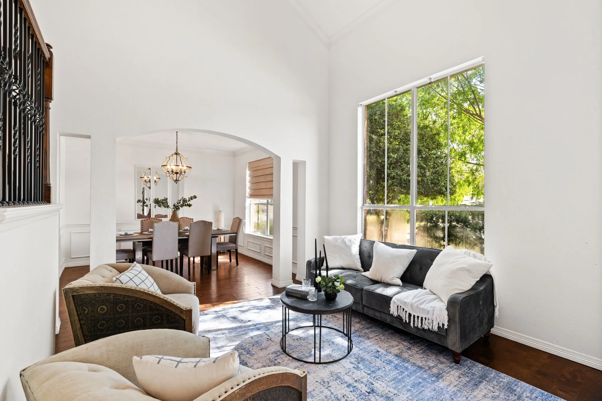 Living area featuring ornamental molding, a high ceiling, wood finished floors, suspended lighting, and arched walkways
