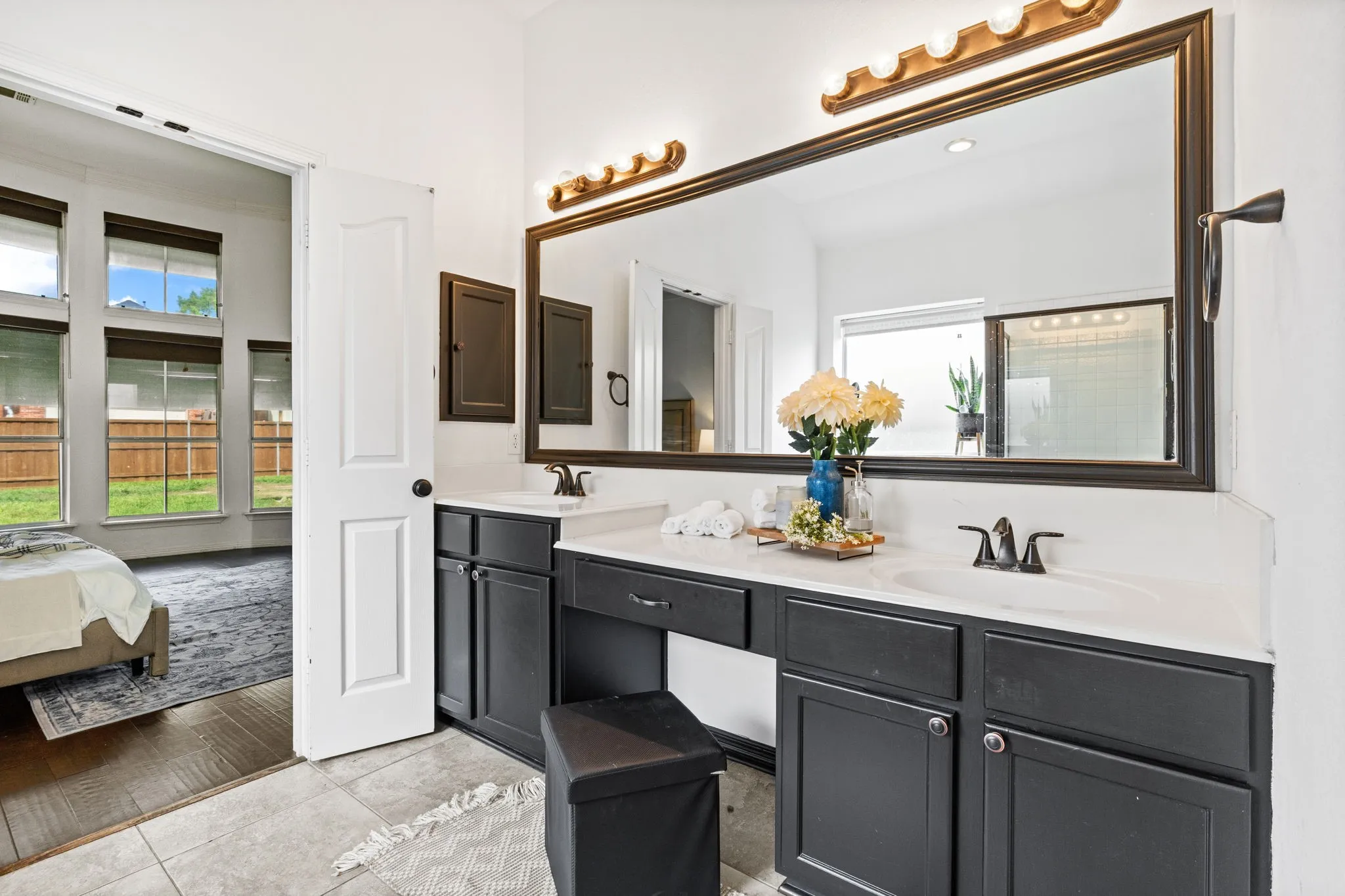 Bathroom with connected bathroom, double vanity, and light tile patterned floors