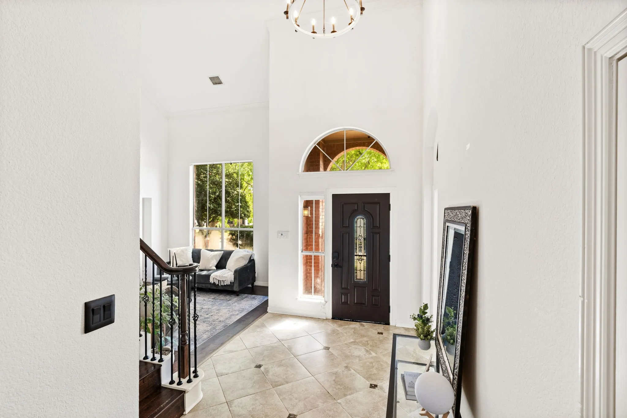 Foyer entrance featuring a high ceiling, a textured wall, hanging lights, and light tile patterned flooring