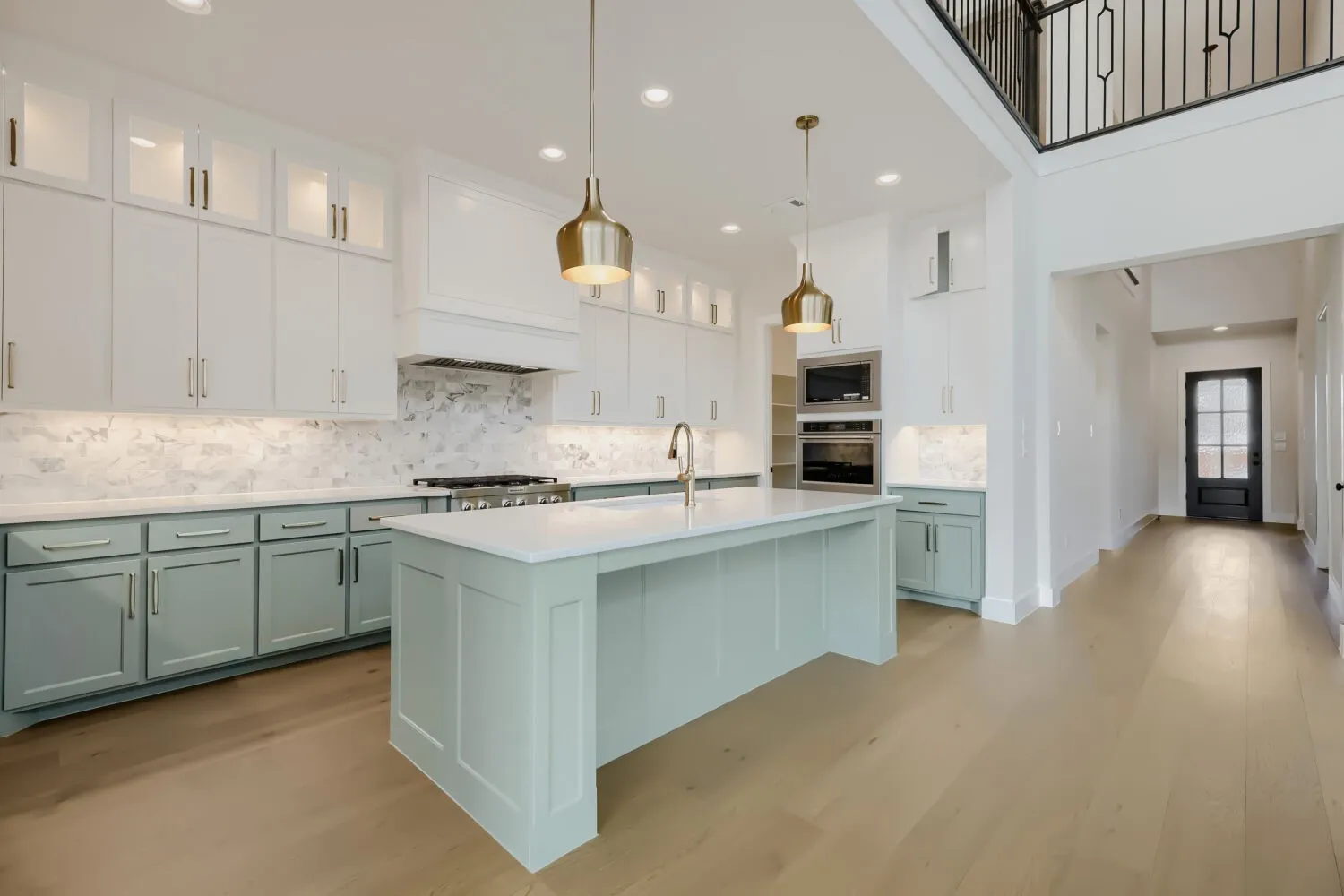 Open-concept kitchen featuring two-tone cabinetry, a central island with a sink, stainless steel appliances, and wood-finish flooring