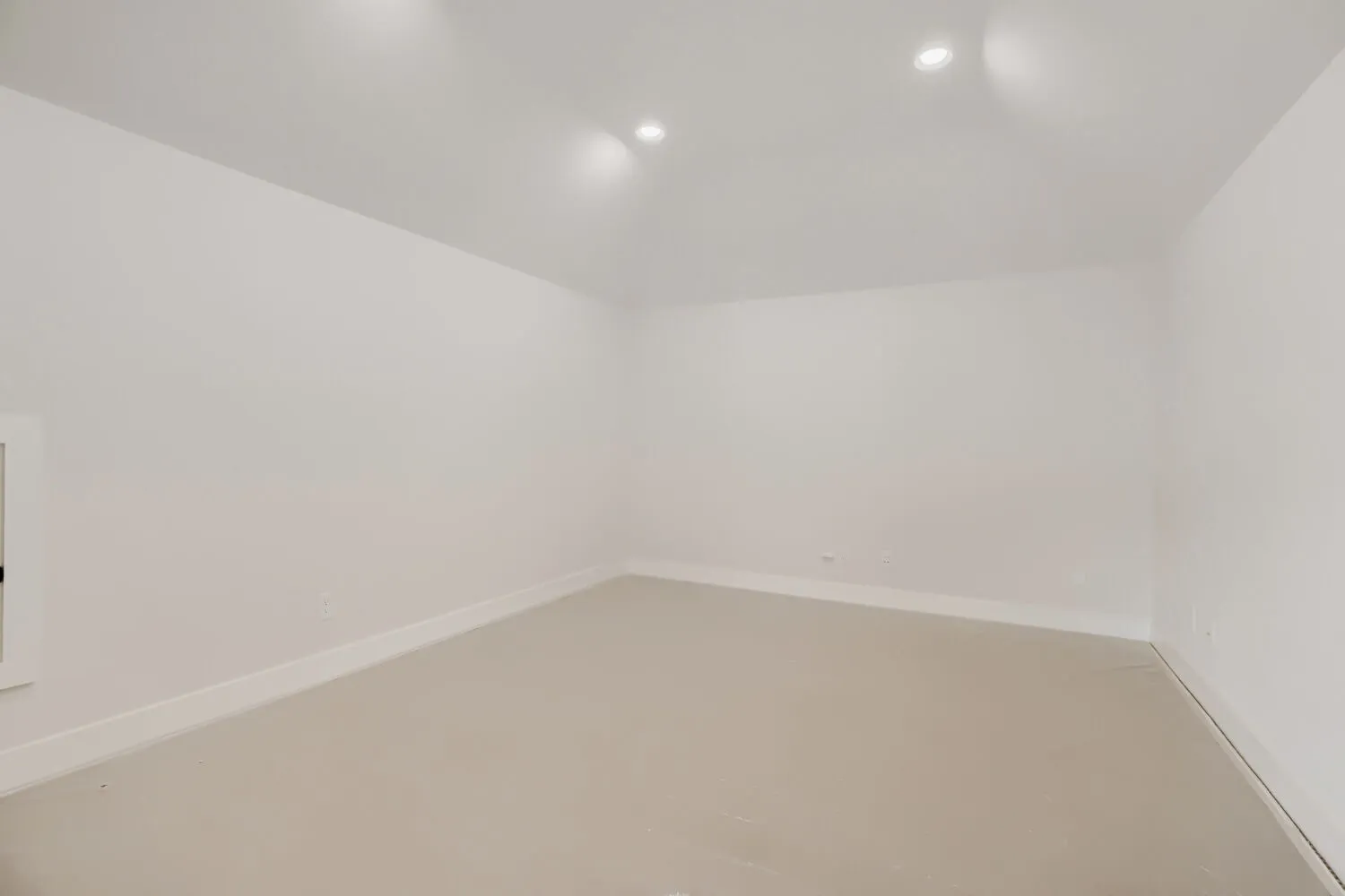 Spacious interior room featuring light-toned flooring, white walls, and recessed ceiling lighting