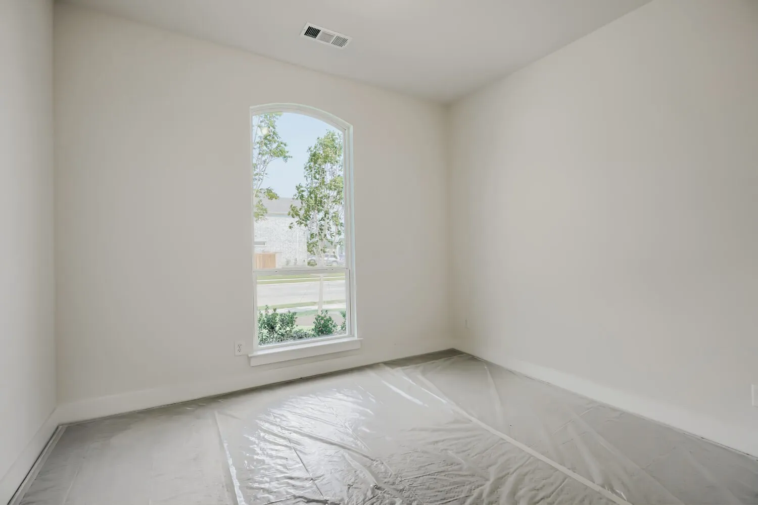 Expansive room featuring a large arched window with white trim, offering views of the exterior landscape