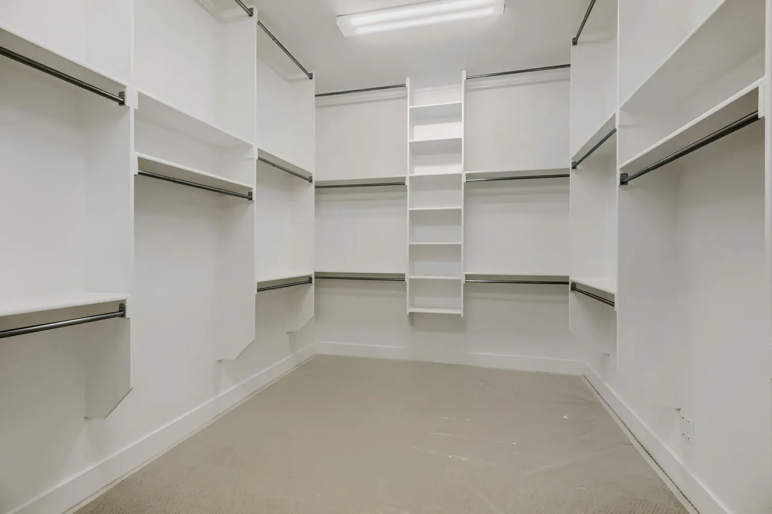 Walk-in closet featuring extensive built-in shelving, multiple hanging rods, corner shelving unit, white baseboards, and neutral carpet flooring