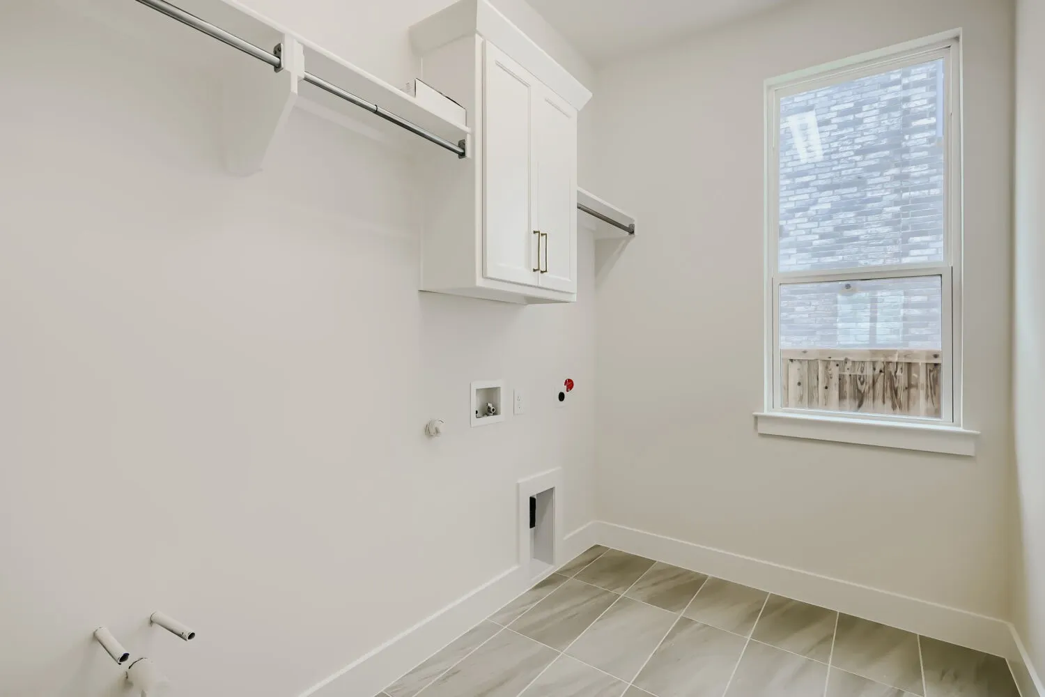 Laundry room featuring a single window, white baseboard trim, and tile flooring