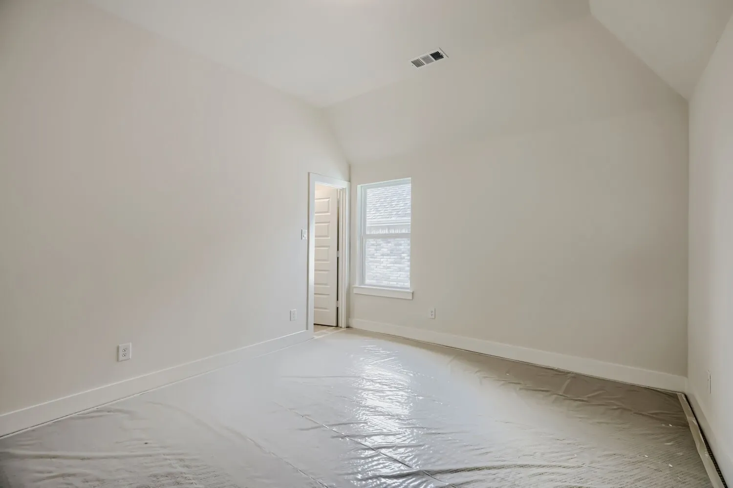 Room featuring vaulted ceilings, neutral-toned walls, and a single window with white trim