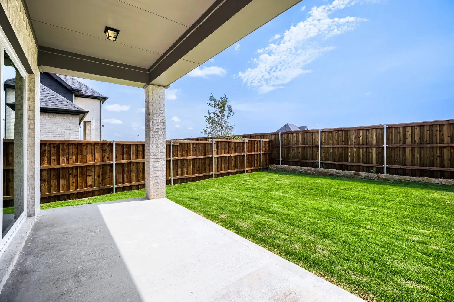 Covered patio with a concrete slab and a brick-wrapped support column