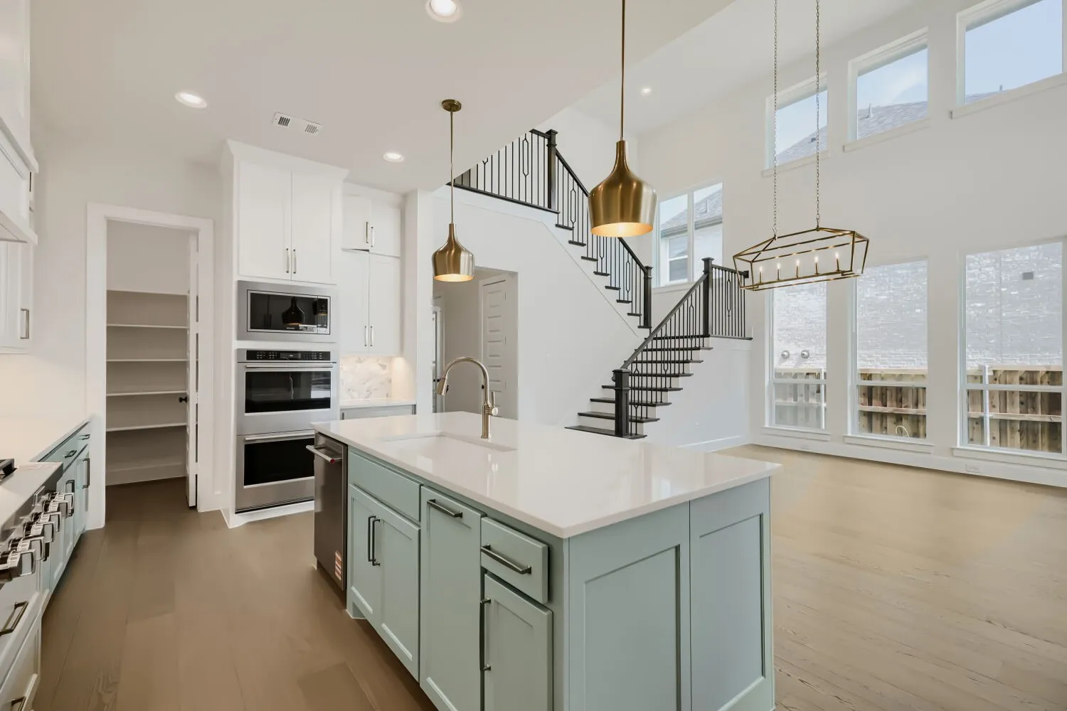 Gourmet kitchen with a light blue island, white countertops, built-in stainless steel appliances, and wood-finish flooring