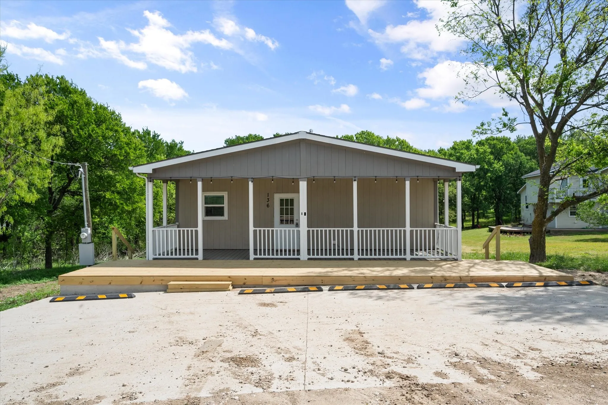 Inviting front exterior features a spacious covered porch with new decking perfect for outdoor gatherings and lake-area relaxation.