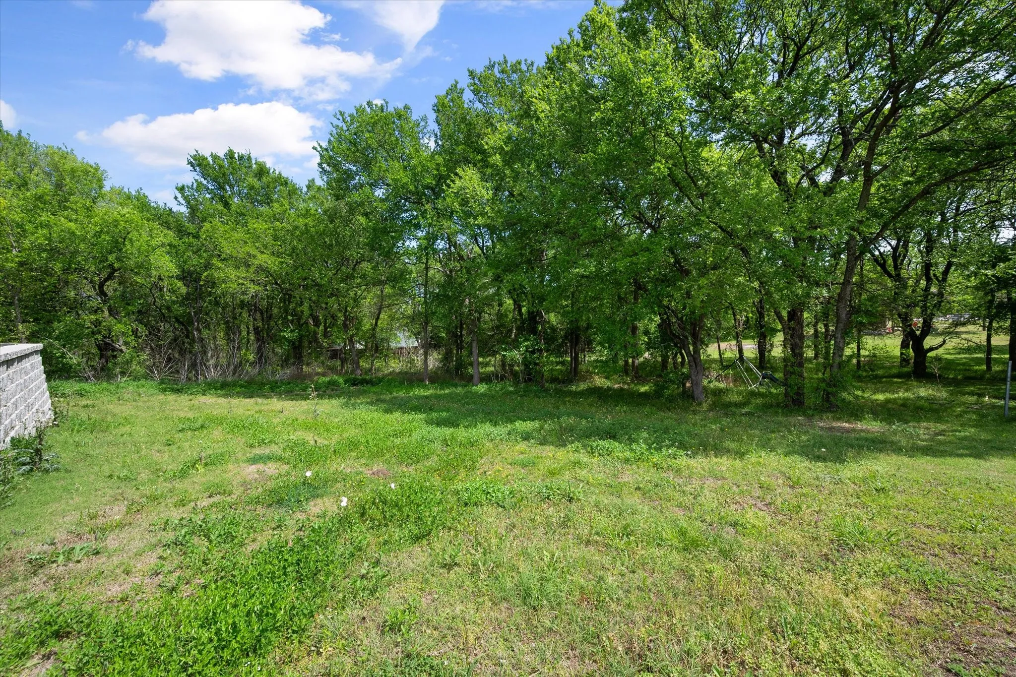 Tree-lined backyard creates a private outdoor retreat perfect for relaxing, entertaining, or enjoying quiet mornings outdoors.