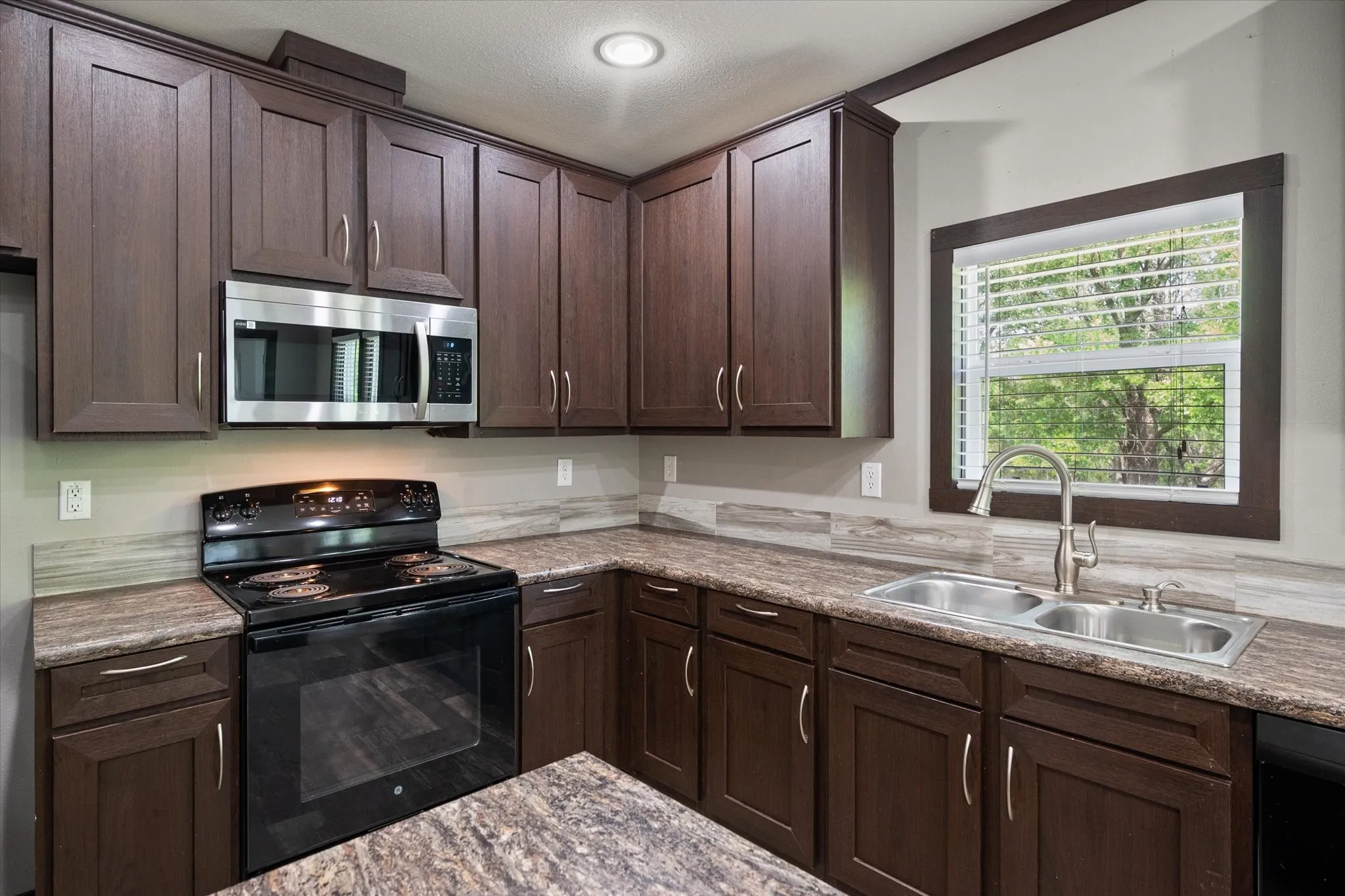 Modern kitchen with rich cabinetry, ample counter space, and natural light overlooking the peaceful backyard setting.