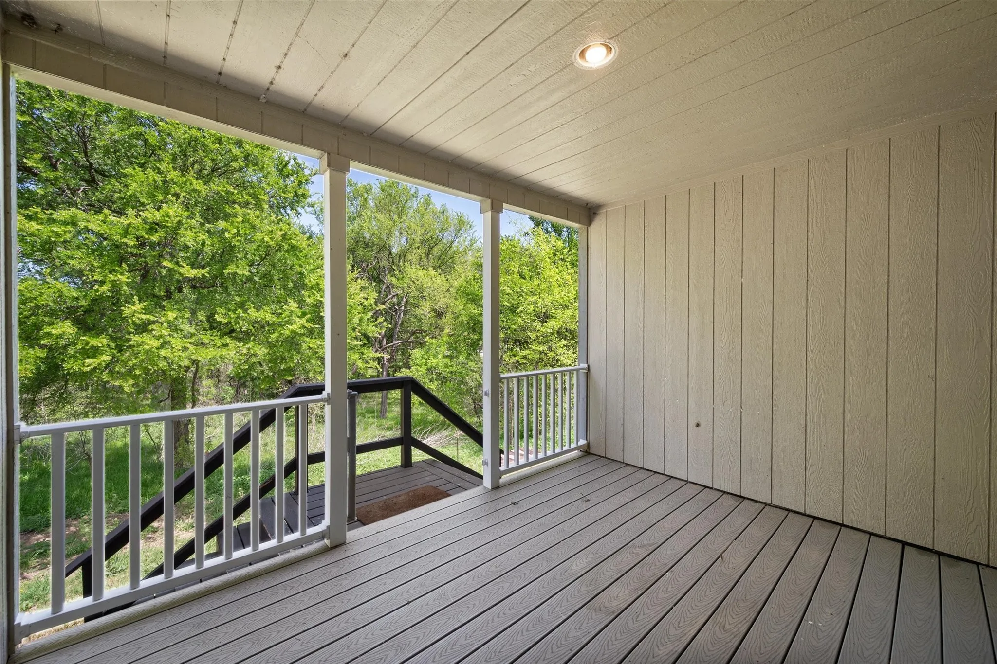 Covered back porch offers a peaceful outdoor retreat surrounded by mature trees and quiet Central Texas scenery.