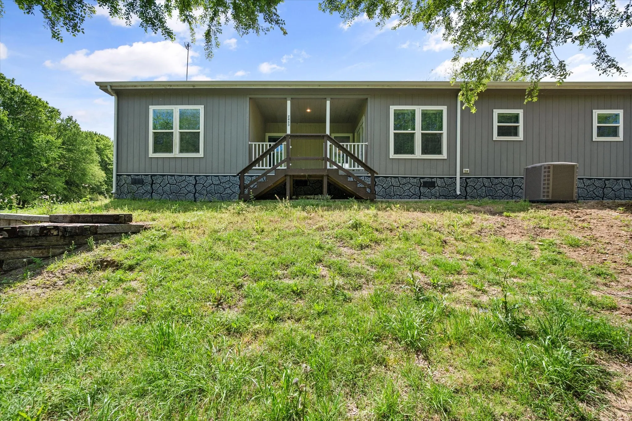 Rear exterior highlights the spacious covered porch and peaceful setting ideal for weekend escapes or full-time lake living.