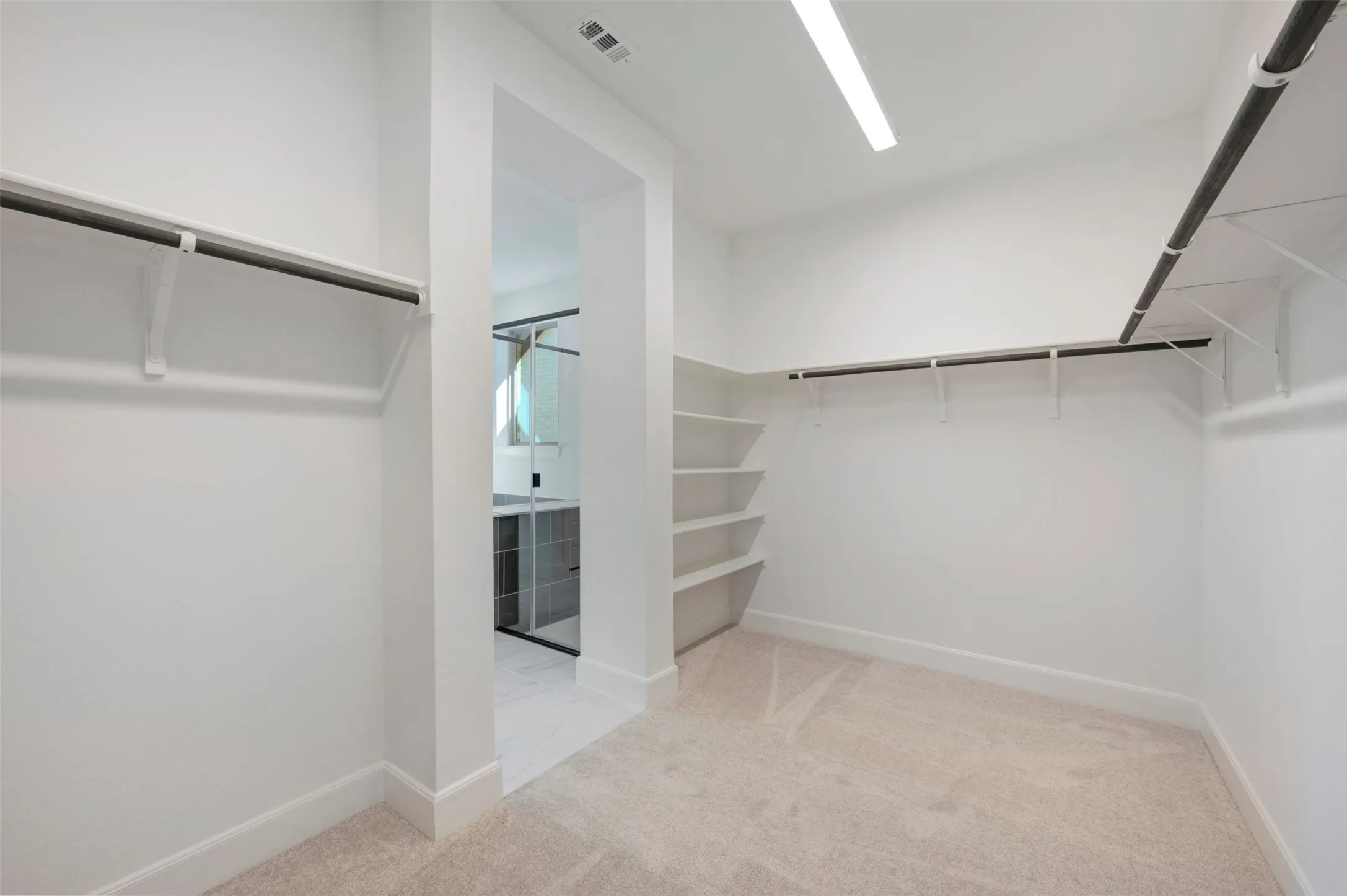 Spacious closet featuring wall-mounted shelving and multiple clothing rods