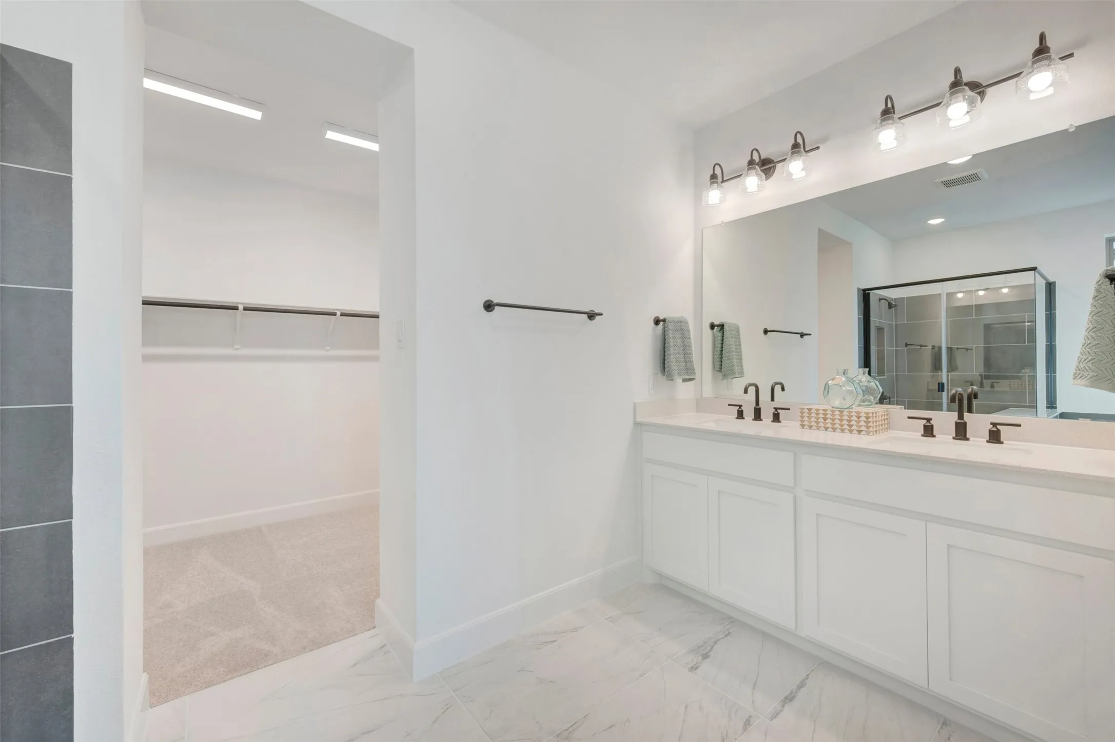Double vanity with white cabinetry, integrated sinks, dark bronze fixtures, and a large wall-mounted mirror