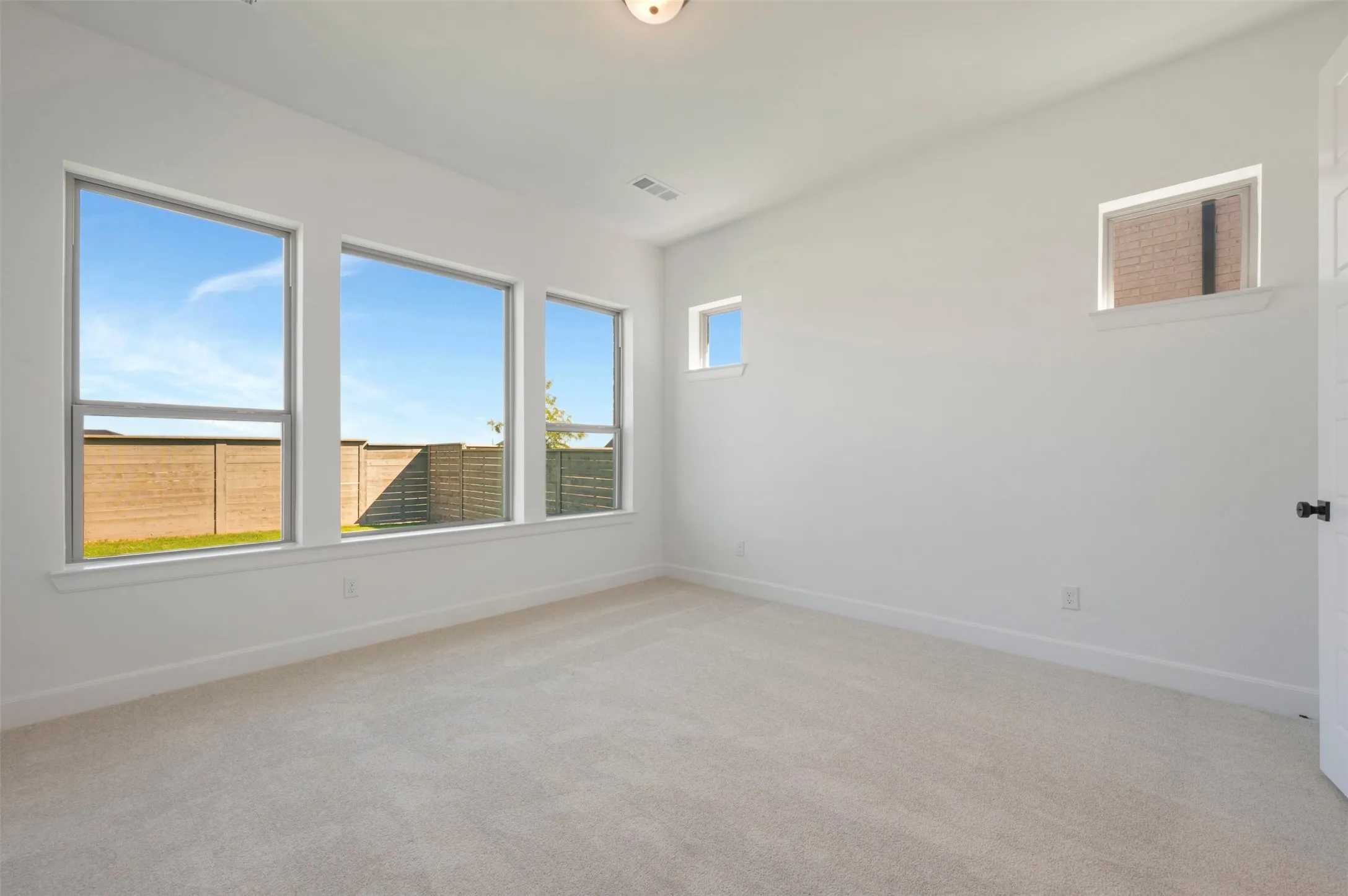 Spacious interior room featuring light-toned carpeting and neutral wall finishes