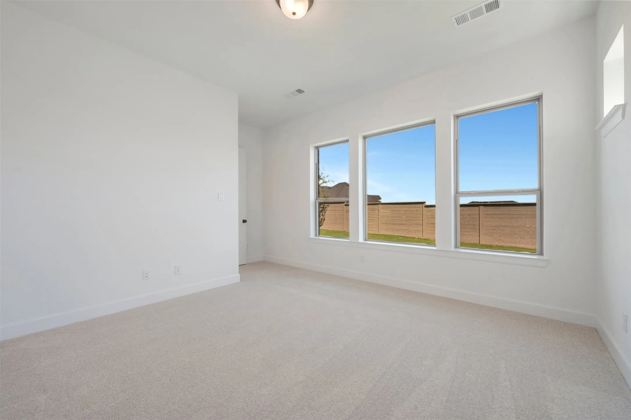 Spacious room with plush light-colored carpeting and white baseboards