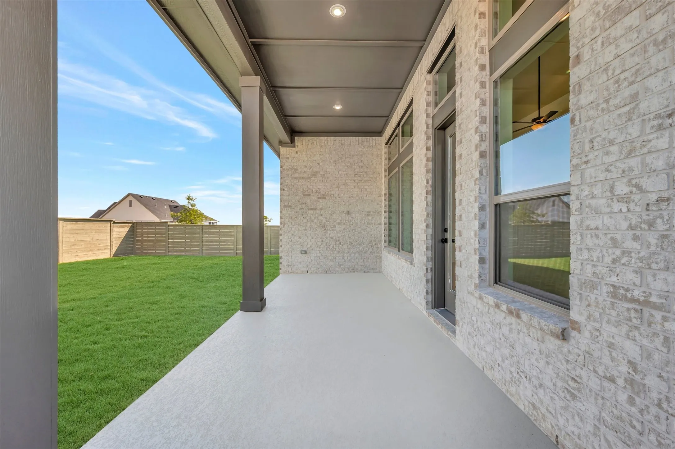 Covered patio with recessed lighting, light brick exterior, and a spacious fenced yard