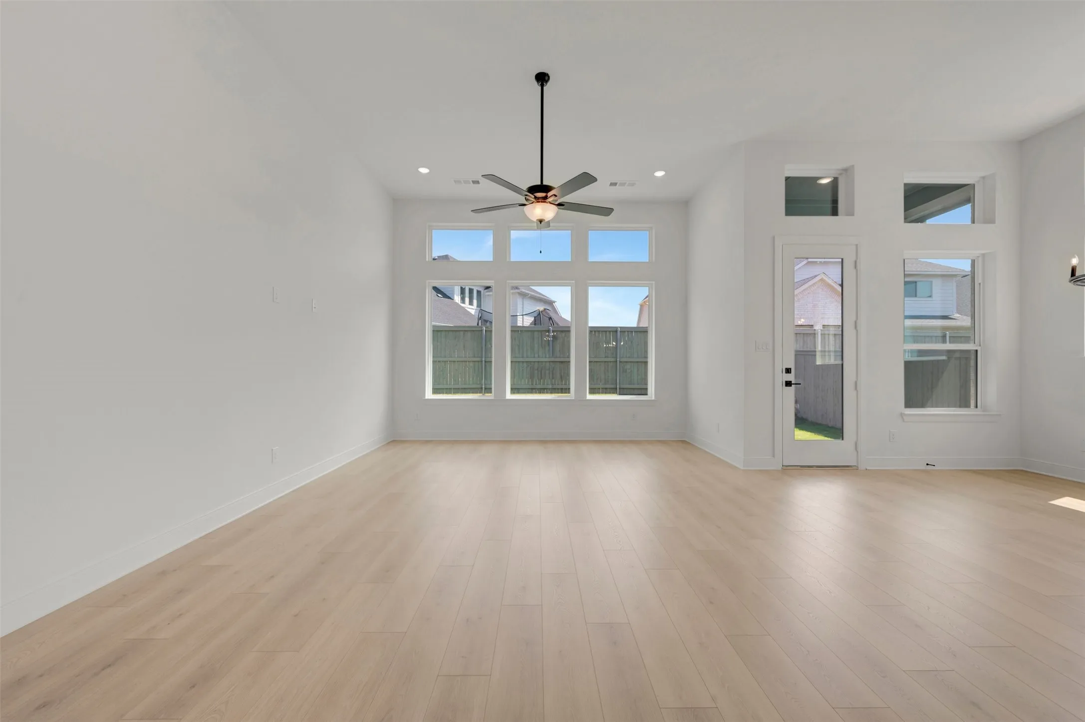 Spacious interior with wood-finish flooring, high ceilings, and recessed lighting