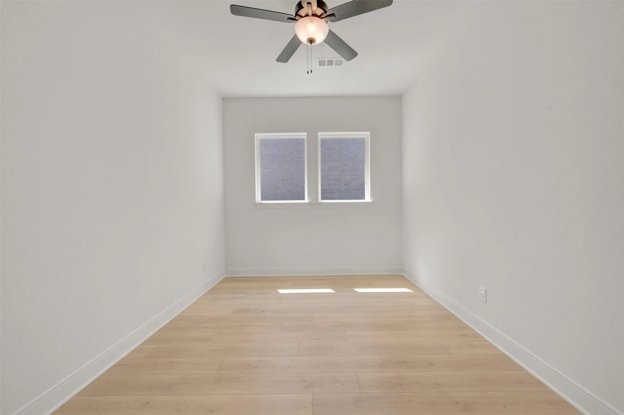 Room featuring wood-finish flooring, two windows with blinds, a ceiling fan with integrated lighting, and white baseboards